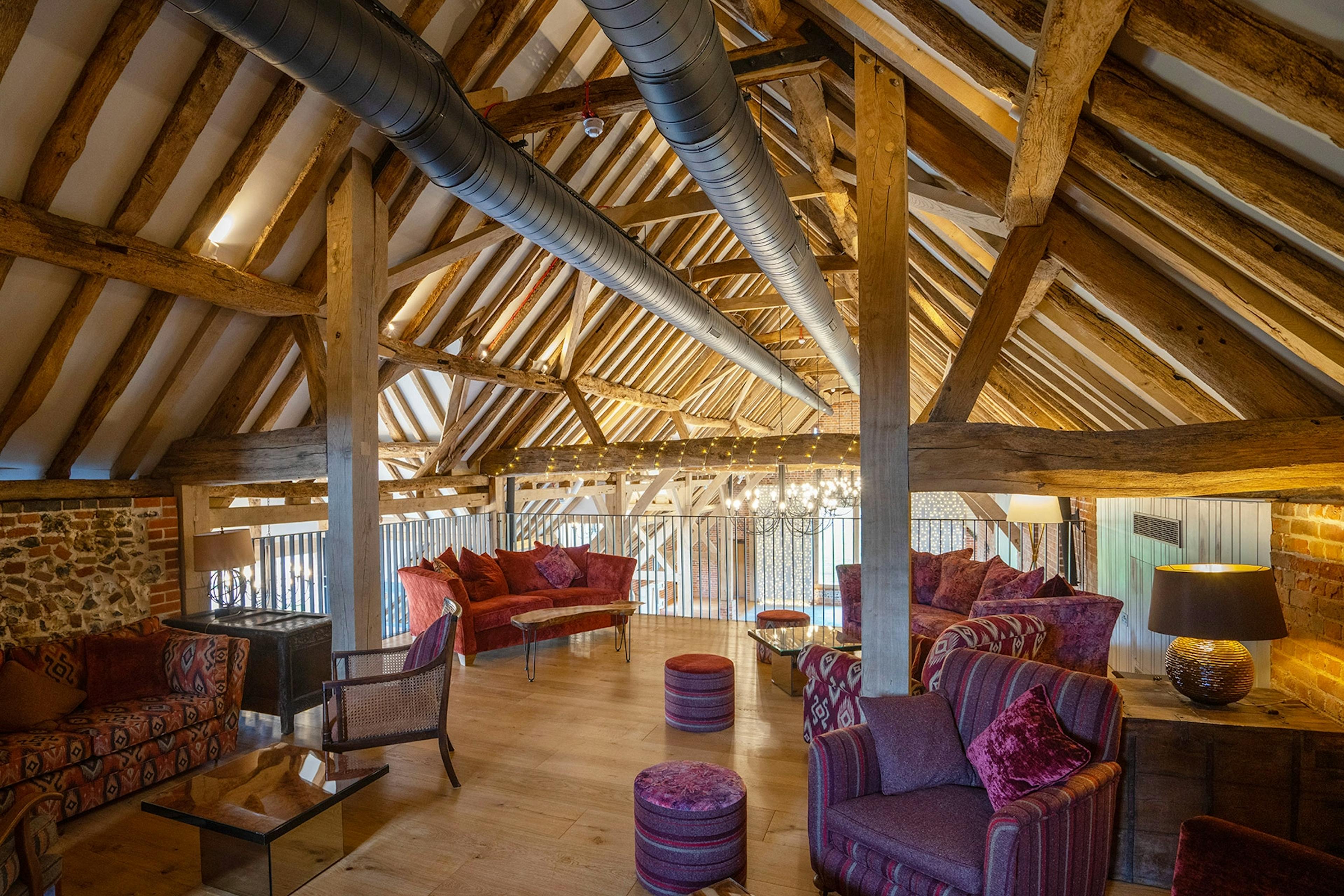 A mezzanine of an oak framed wedding barn hall with sofas and seating areas