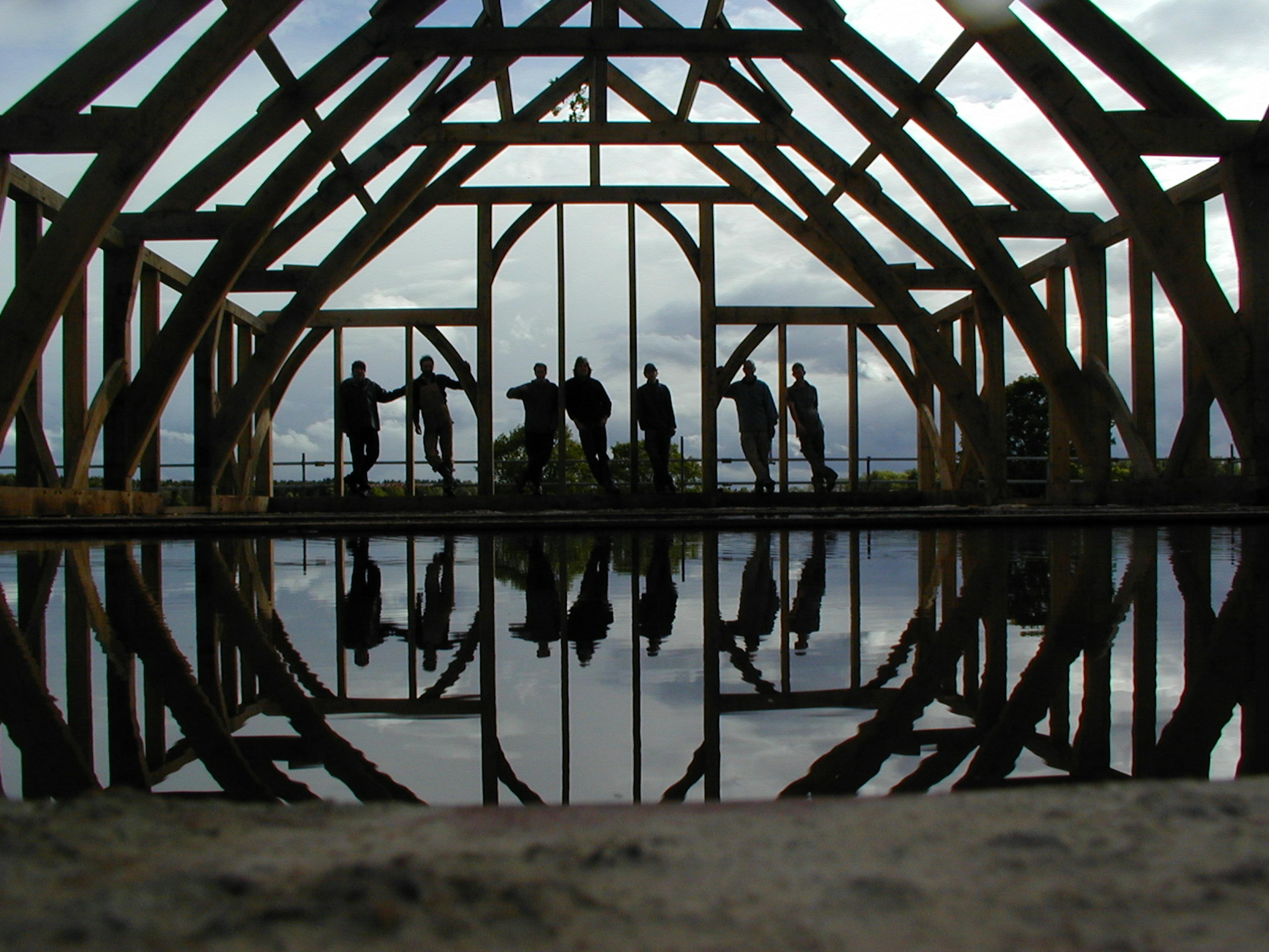 An oak framed wedding barn during construction with site workers silhouetted