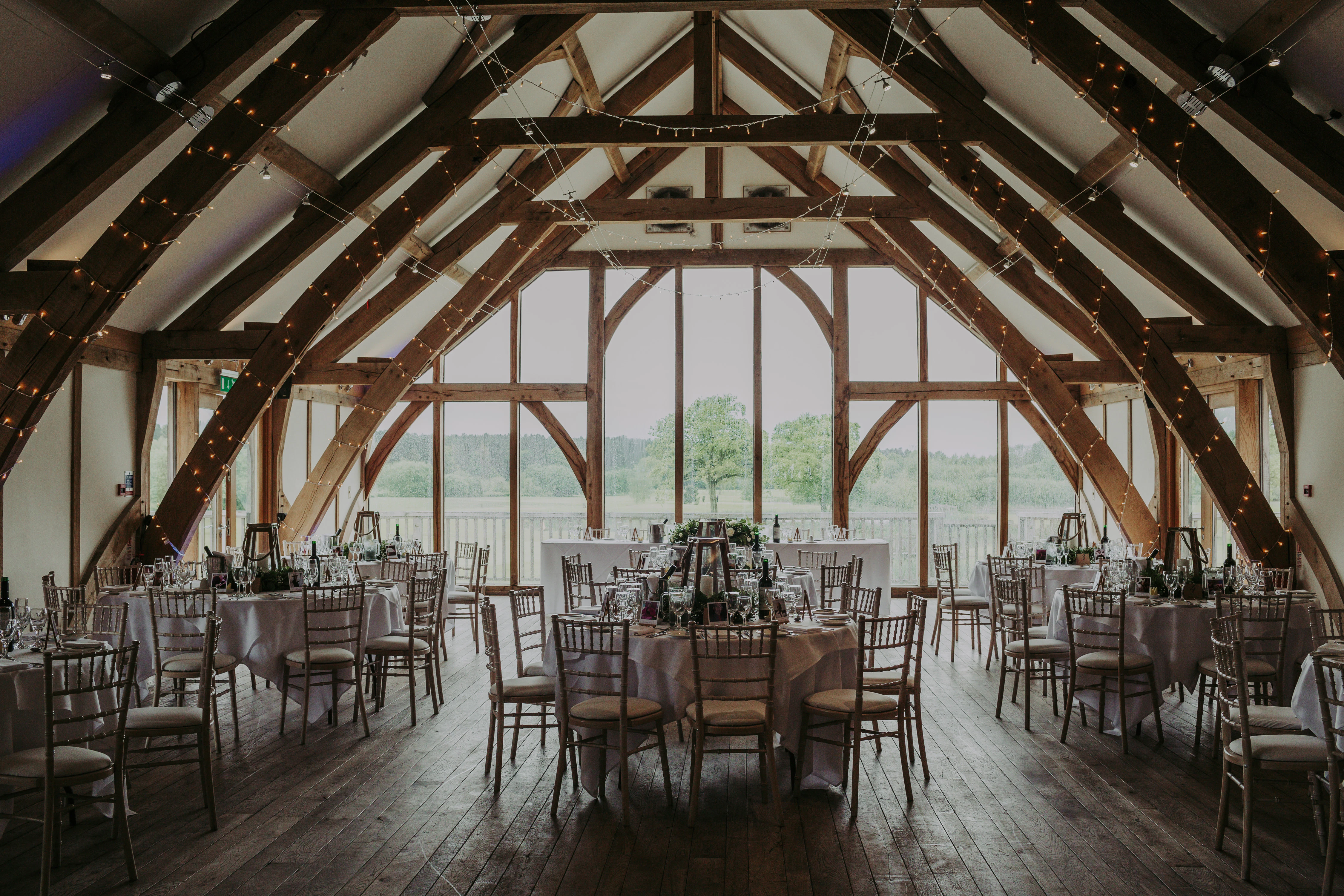 Tables laid for guests in an oak framed wedding barn