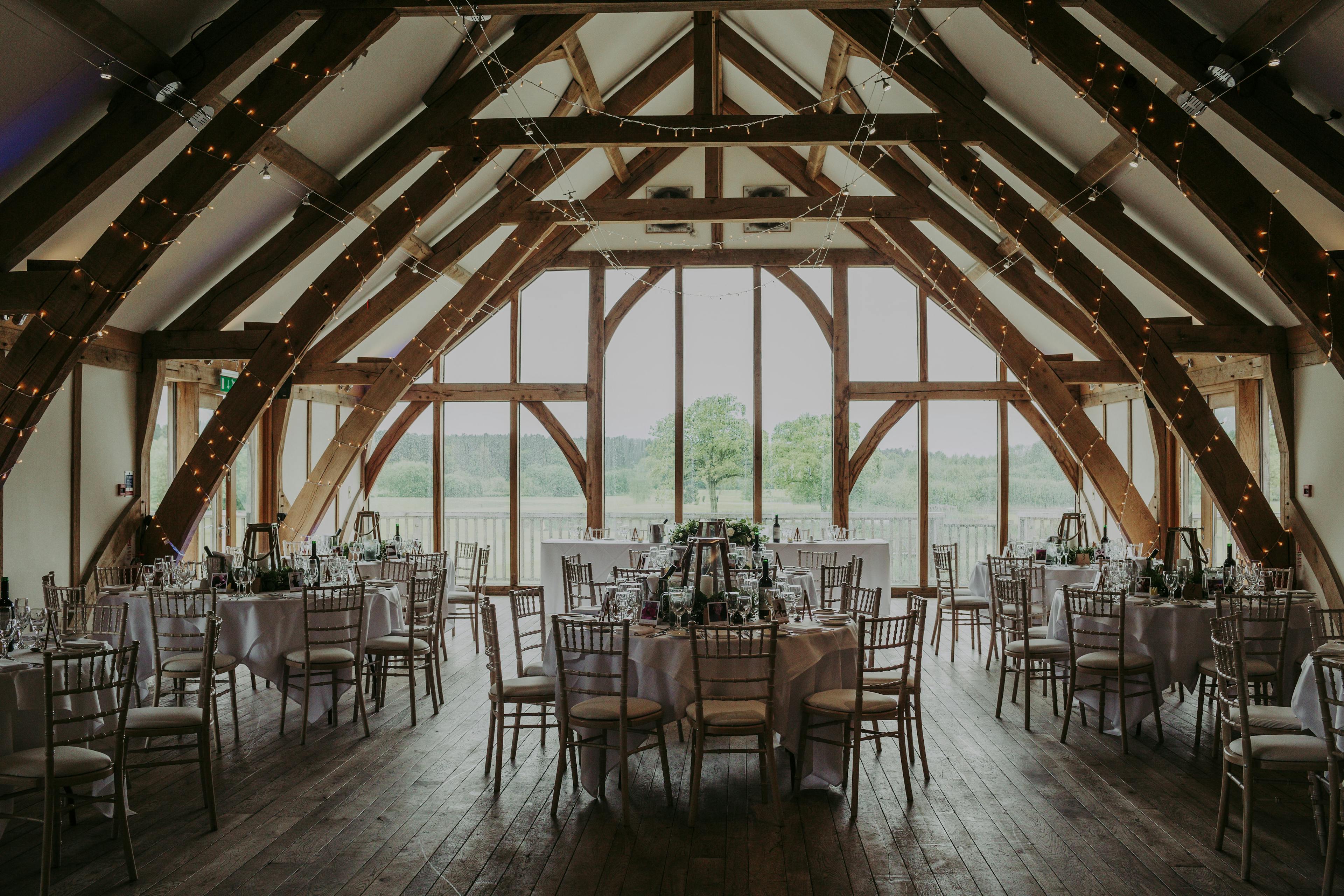 Tables laid for guests in an oak framed wedding barn