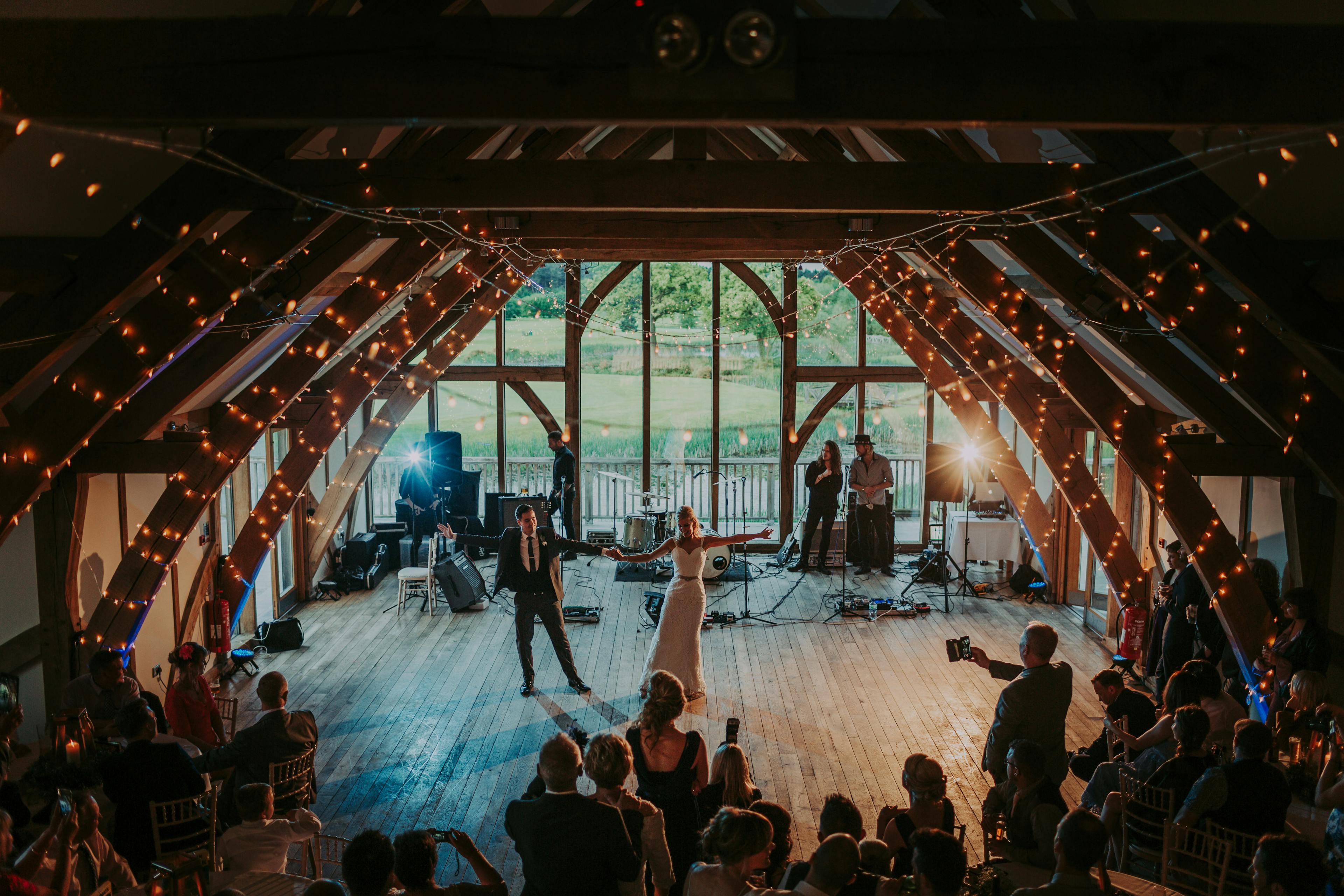 A bride and groom dancing in an oak framed wedding barn