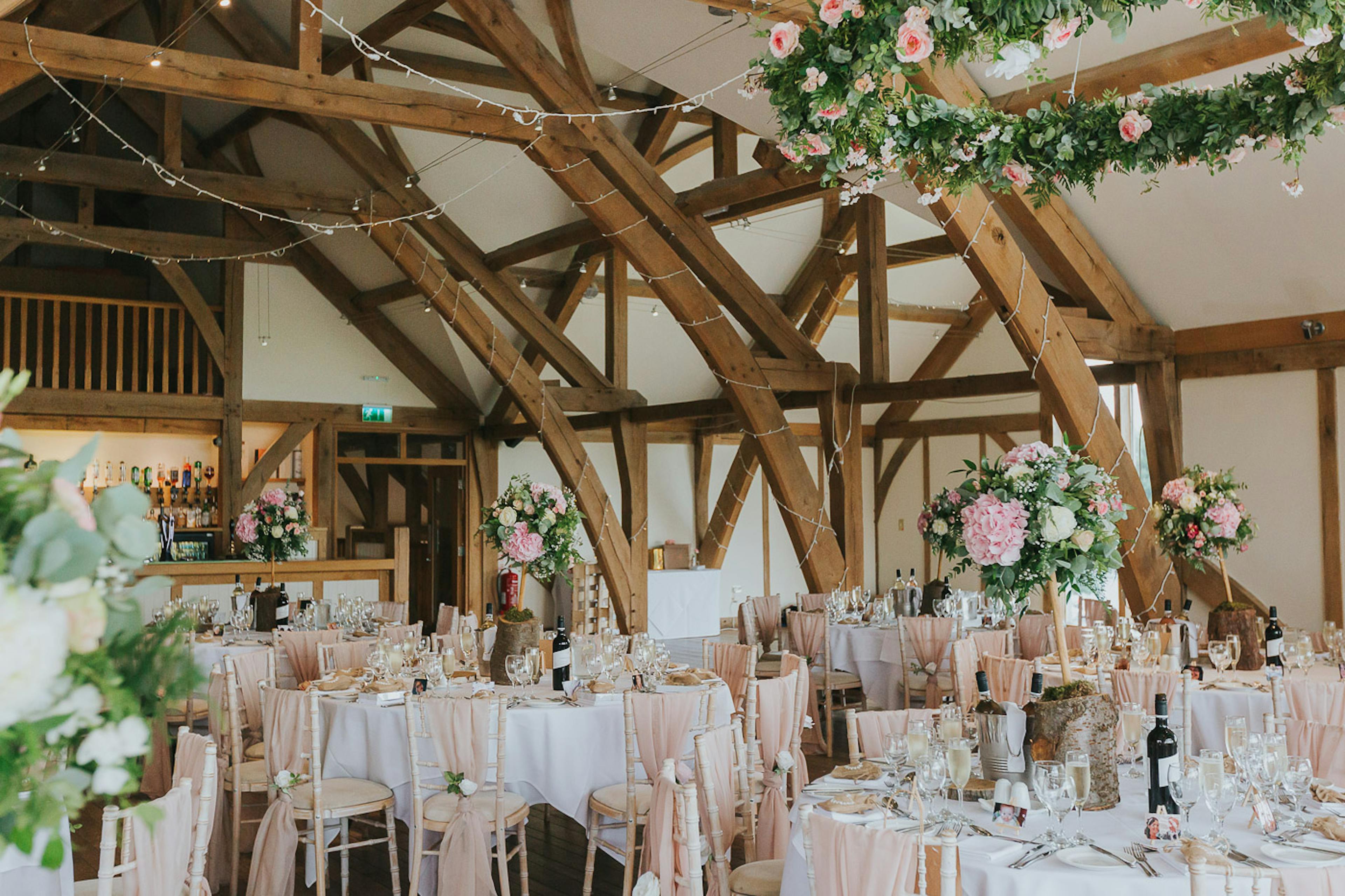 Tables and flowers are ready for guests in an oak framed wedding barn