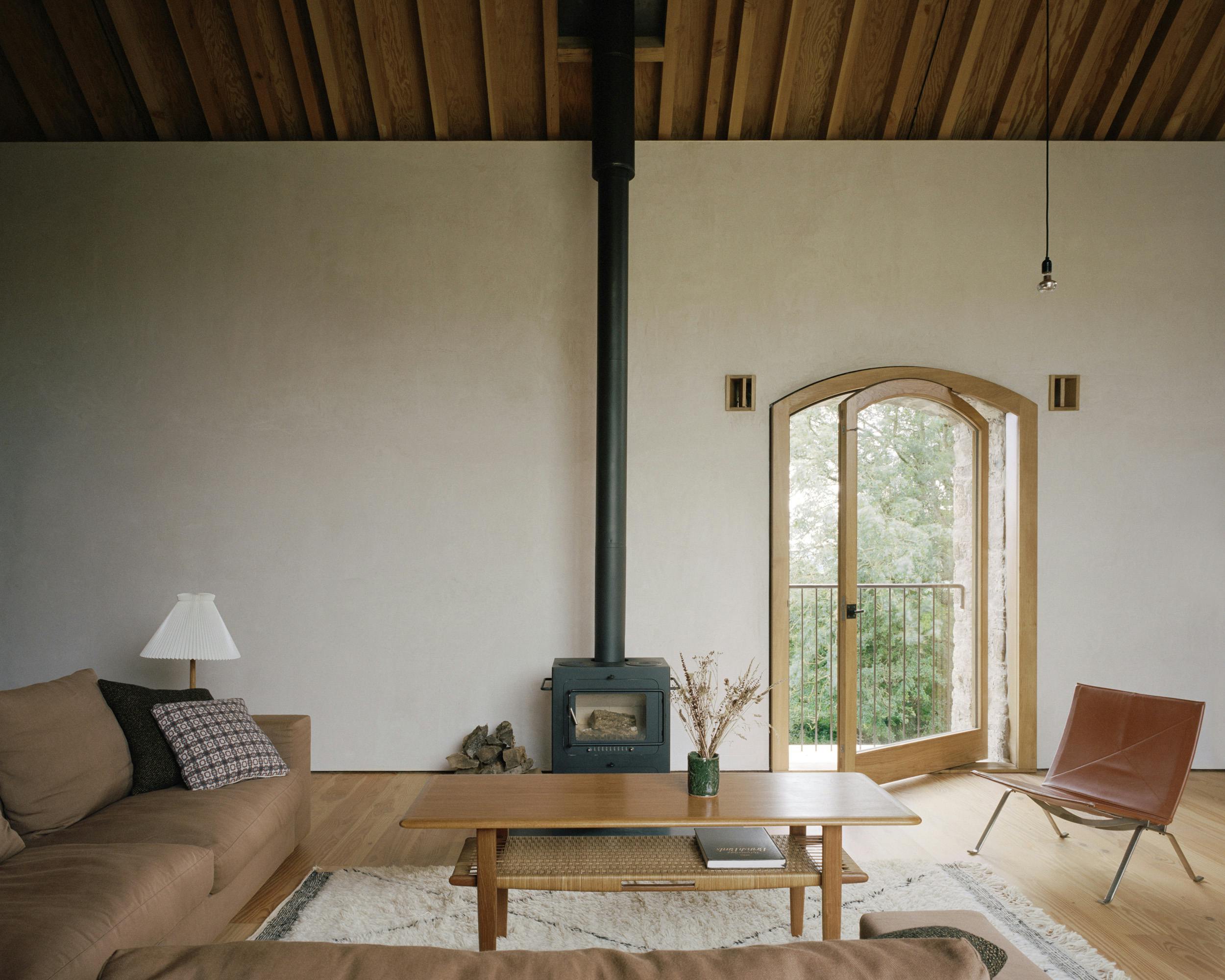 The sitting area with sofa and log burner of a renovated stone barn with a Douglas fir framed roof structure