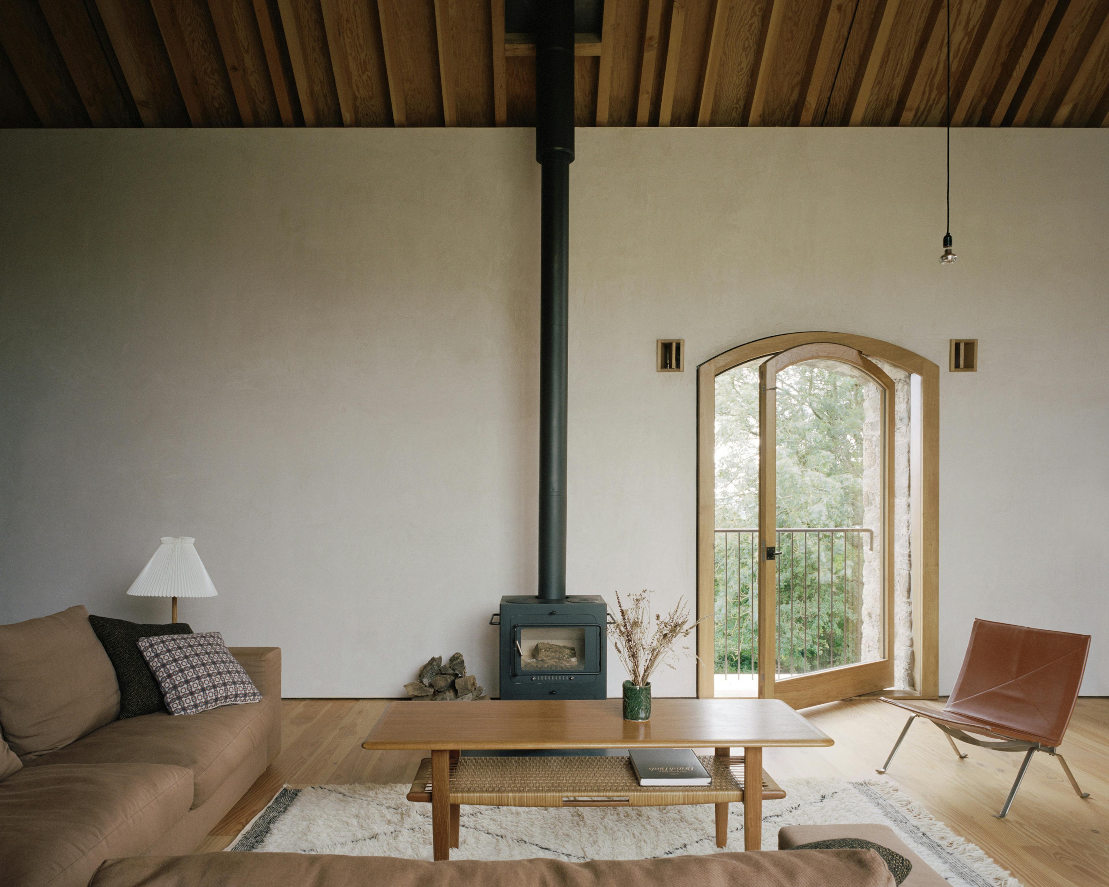 The sitting area with sofa and log burner of a renovated stone barn with a Douglas fir framed roof structure
