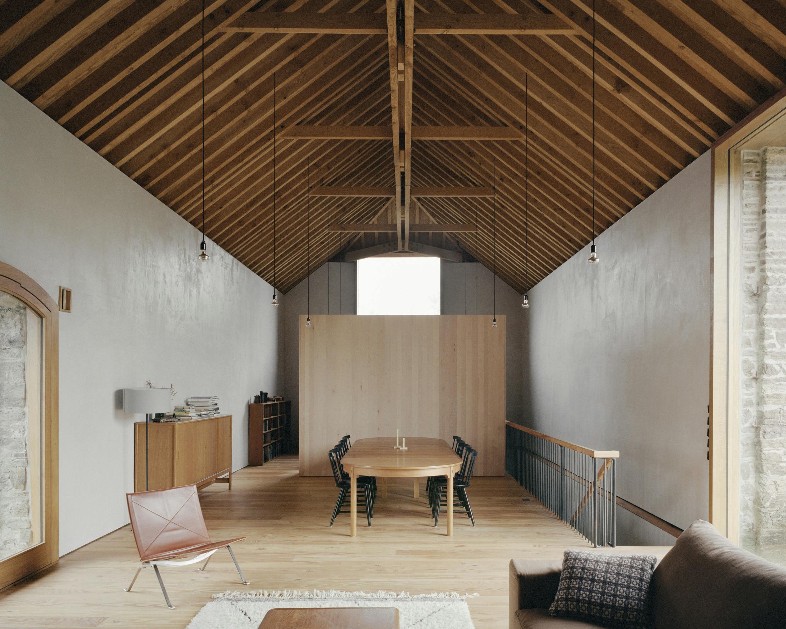 The sitting and dining area of a renovated stone barn with a Douglas fir framed roof structure