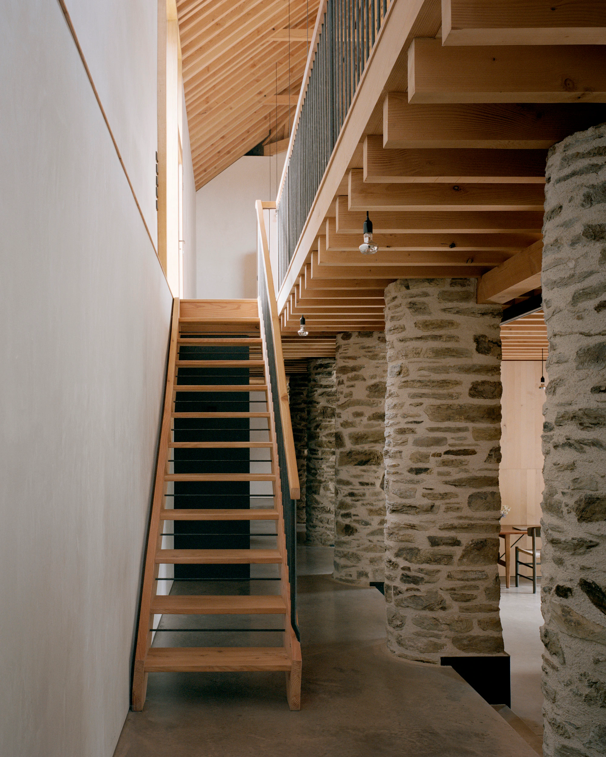 The stairwell of a renovated stone barn with a Douglas fir framed roof structure