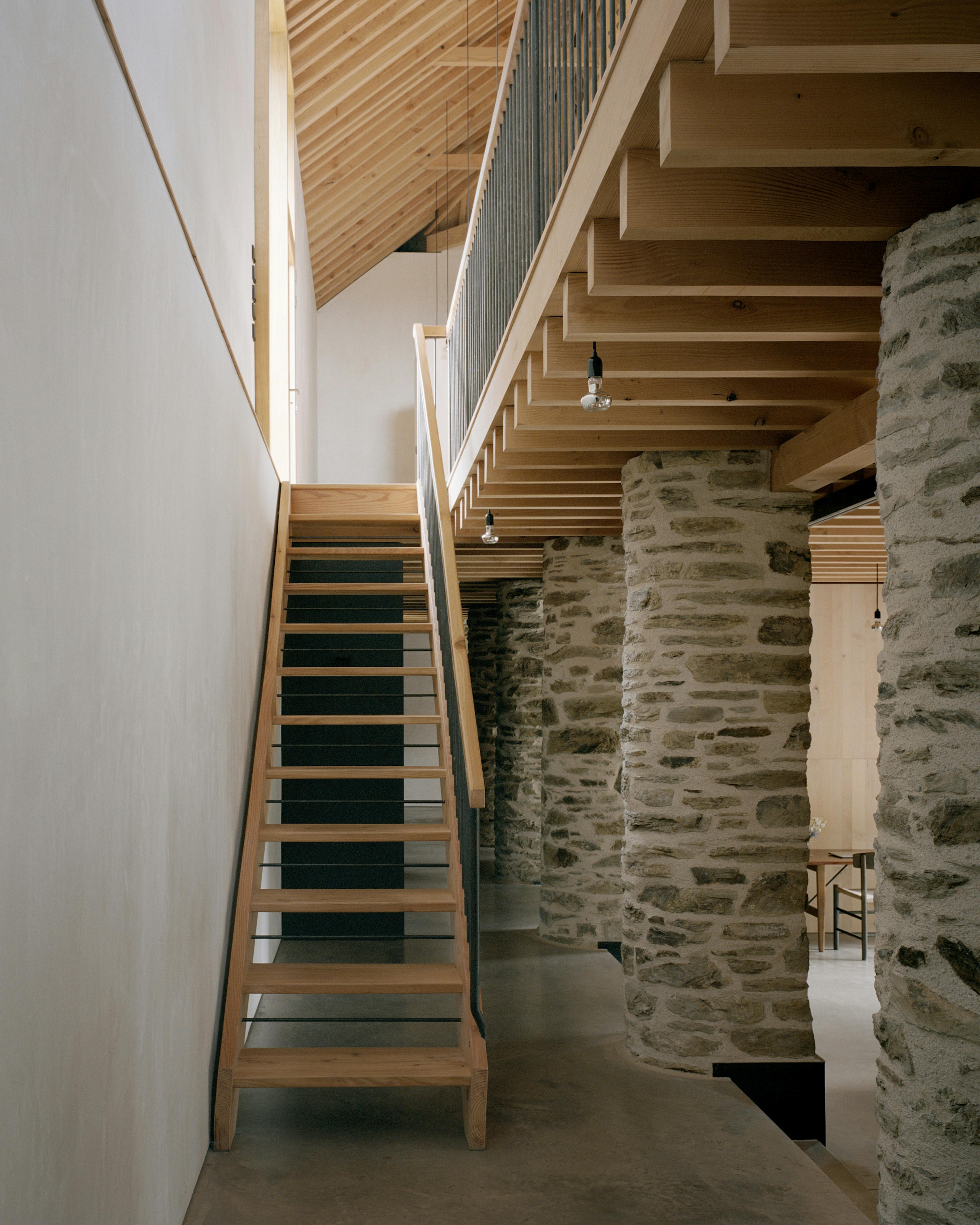 The stairwell of a renovated stone barn with a Douglas fir framed roof structure