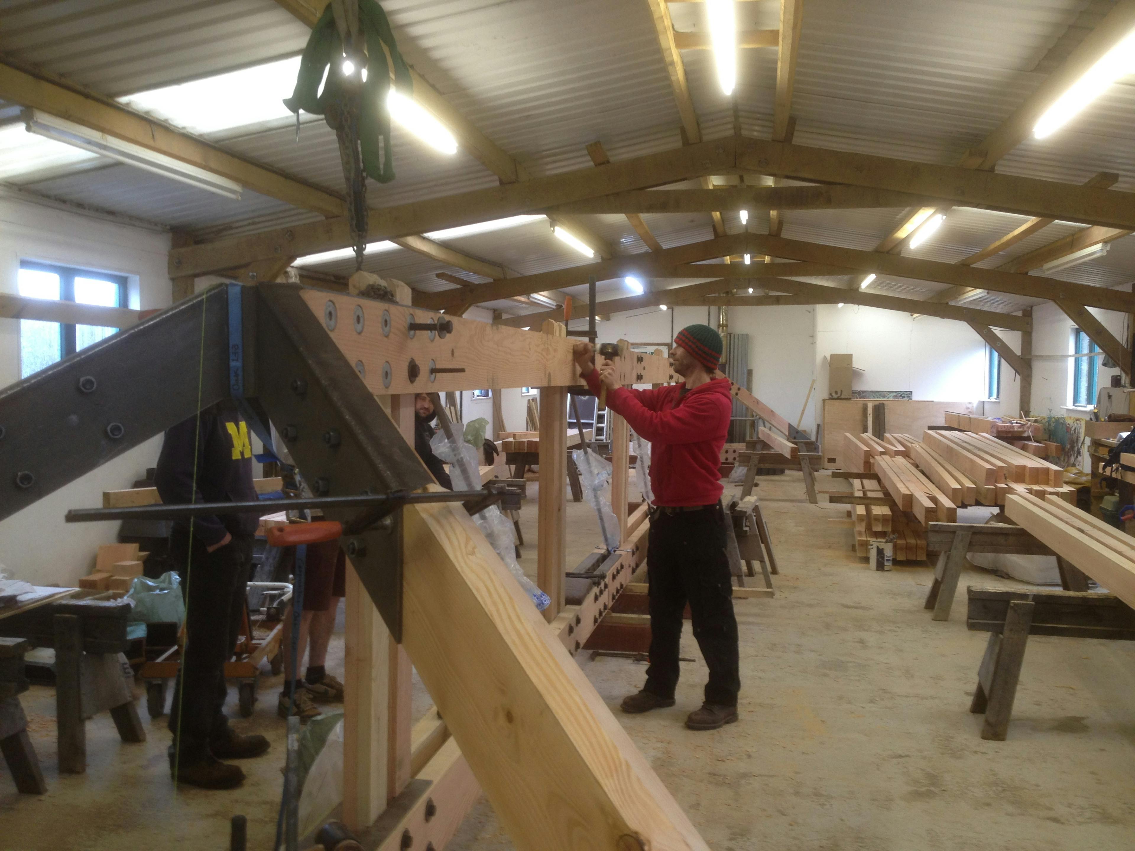 A Douglas fir frame with steel connections being manufactured by hand in a workshop