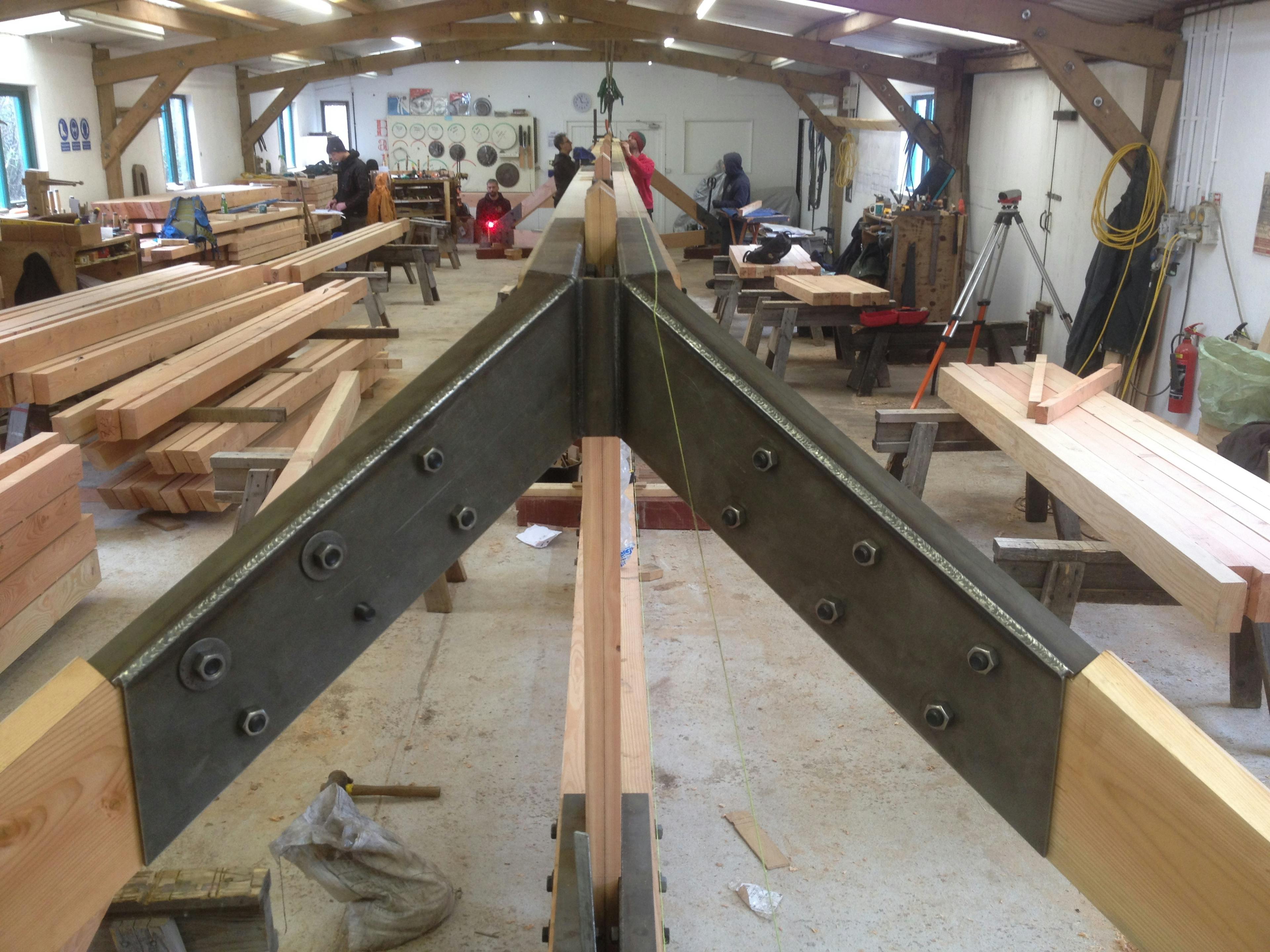 A Douglas fir frame with steel connections being manufactured by hand in a workshop