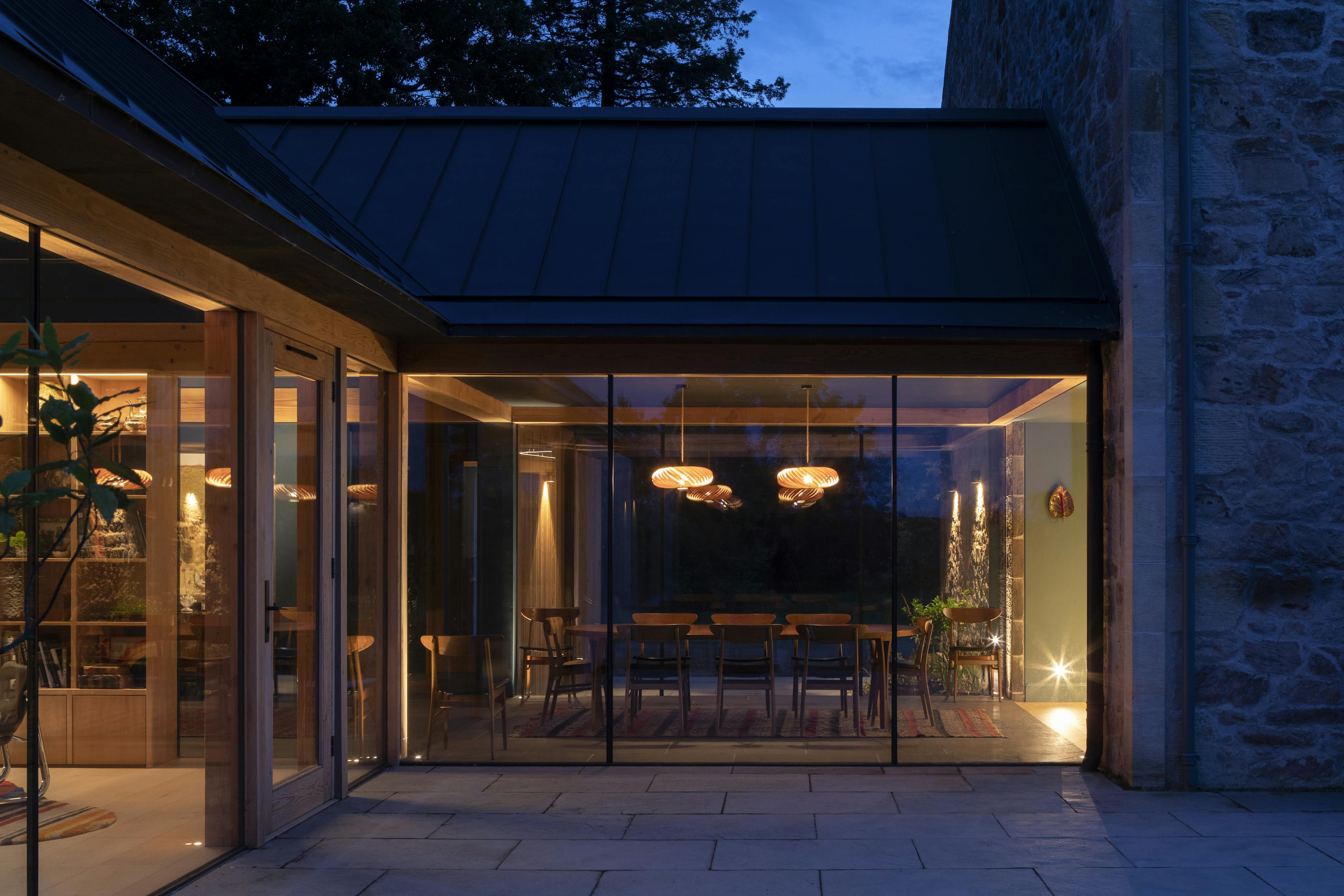 Douglas fir framed dining room extension with glazing at night