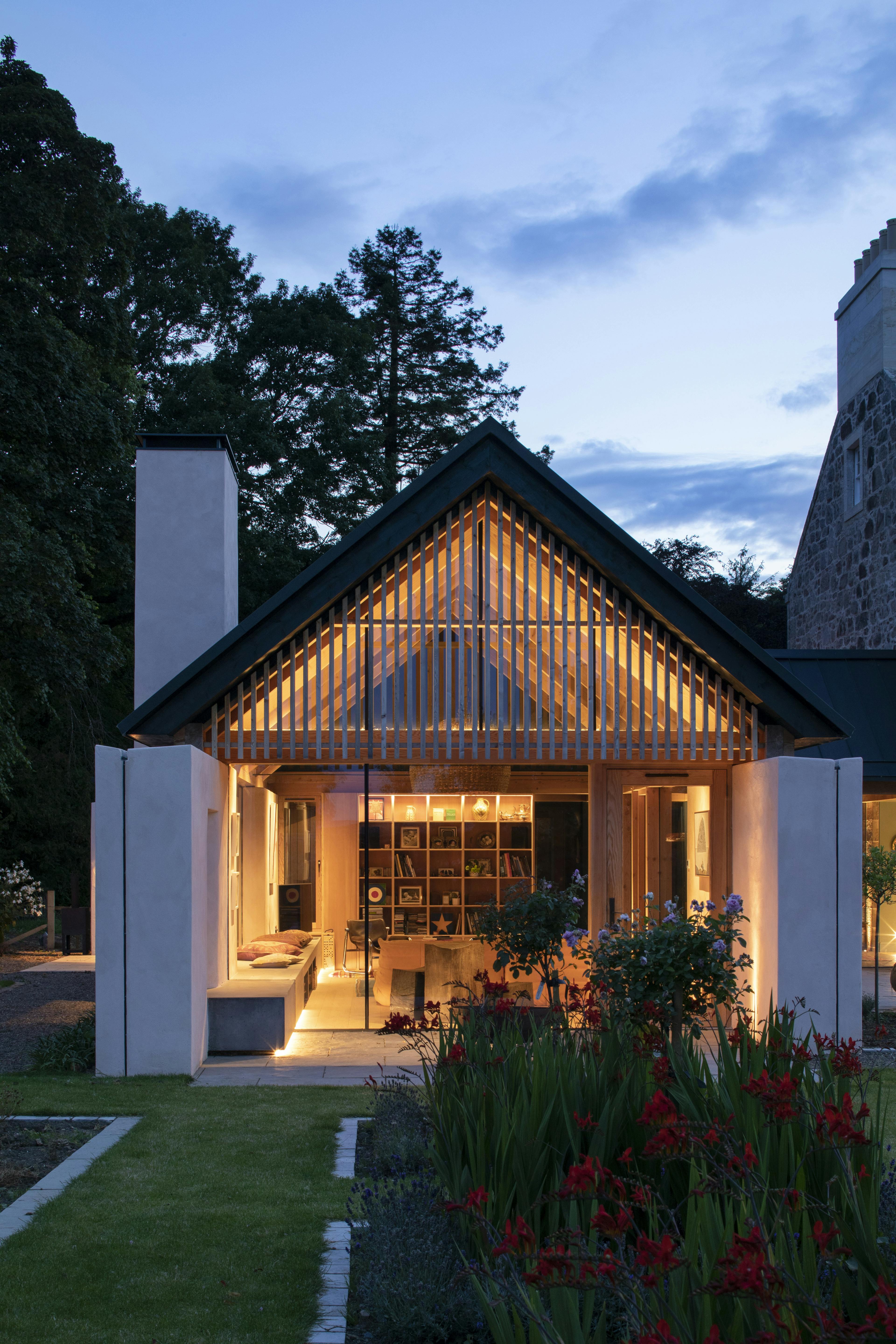 At dusk, light shines from a Douglas fir framed extension set in a garden