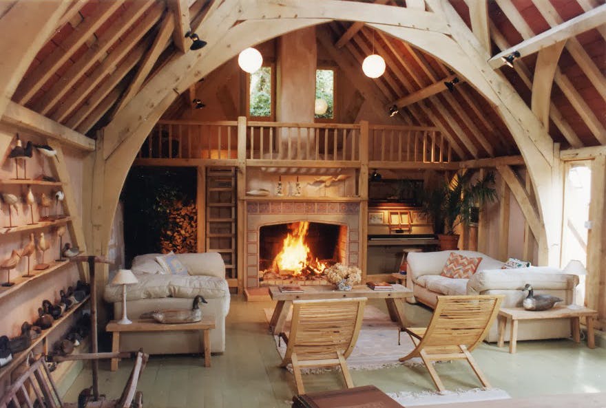A sitting area with a fireplace in an oak framed home with a cruck truss