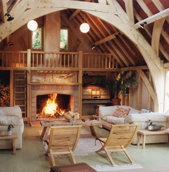 A sitting area with a fireplace in an oak framed home with a cruck truss