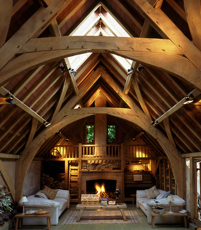 A sitting area with a fireplace in an oak framed home with a cruck truss