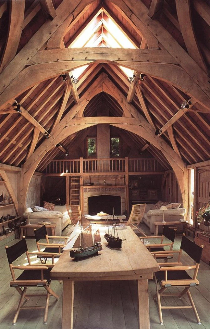 A dining and sitting area with a fireplace in an oak framed home with a cruck truss