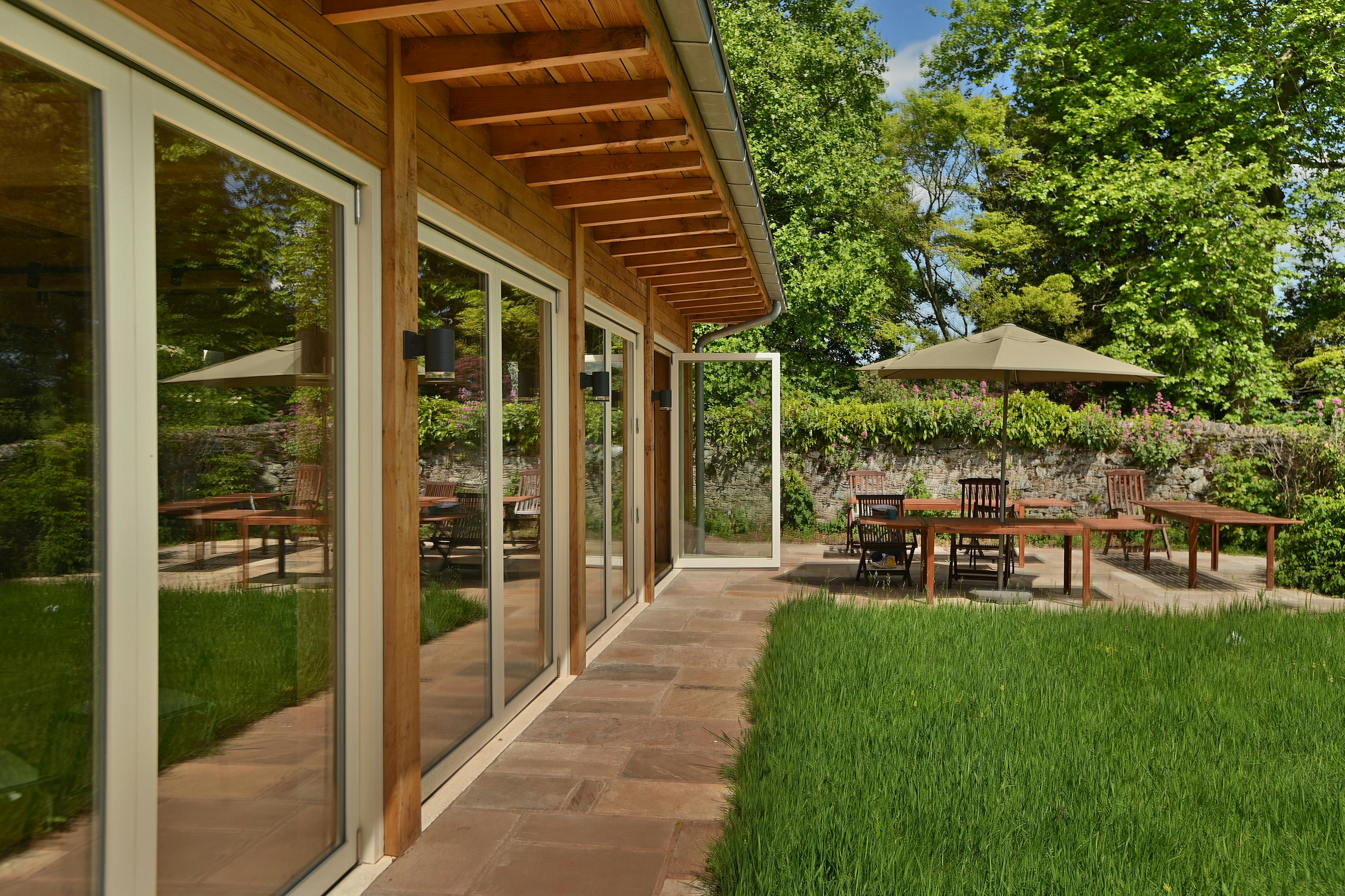 A Douglas fir framed meditation room with a green lawn and outdoor seating outside