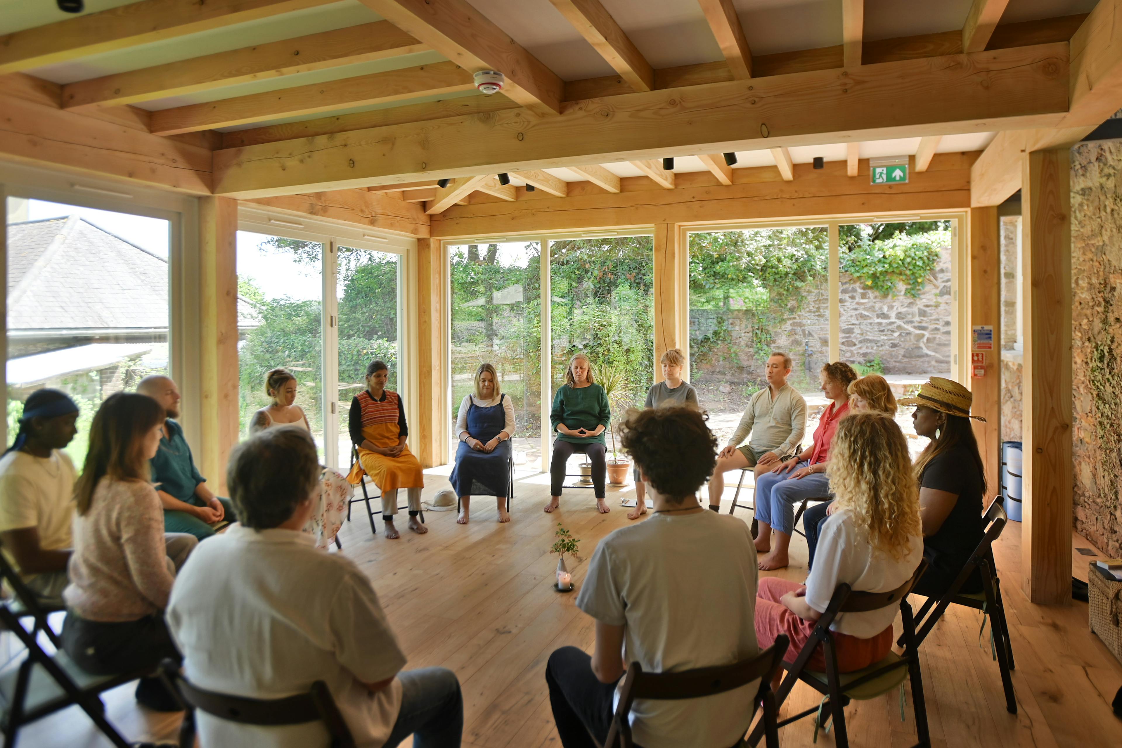 A Douglas fir framed meditation room with people sat on chairs in a circle