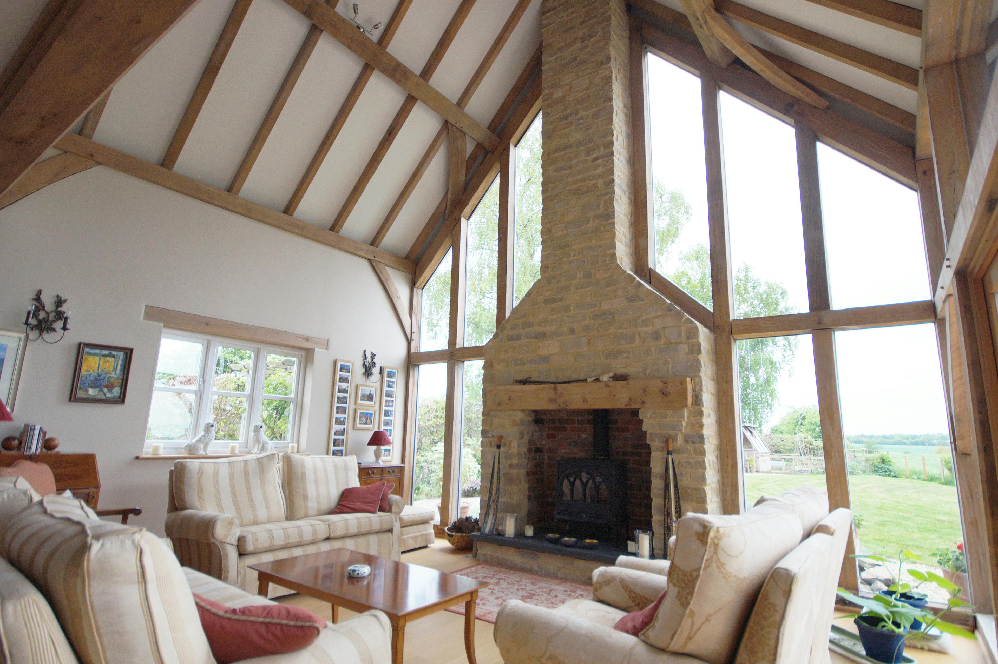 An oak framed sitting room with sofas, log burner and a vaulted ceiling