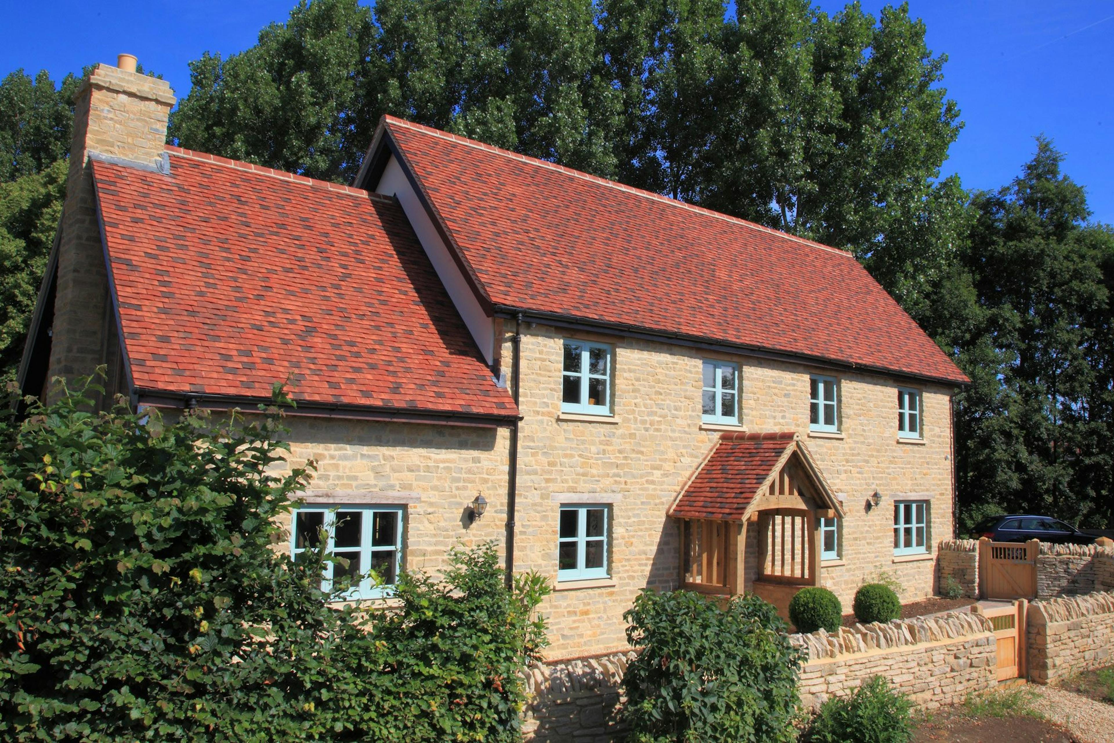 An oak framed home with red tiled roof and an oak porch
