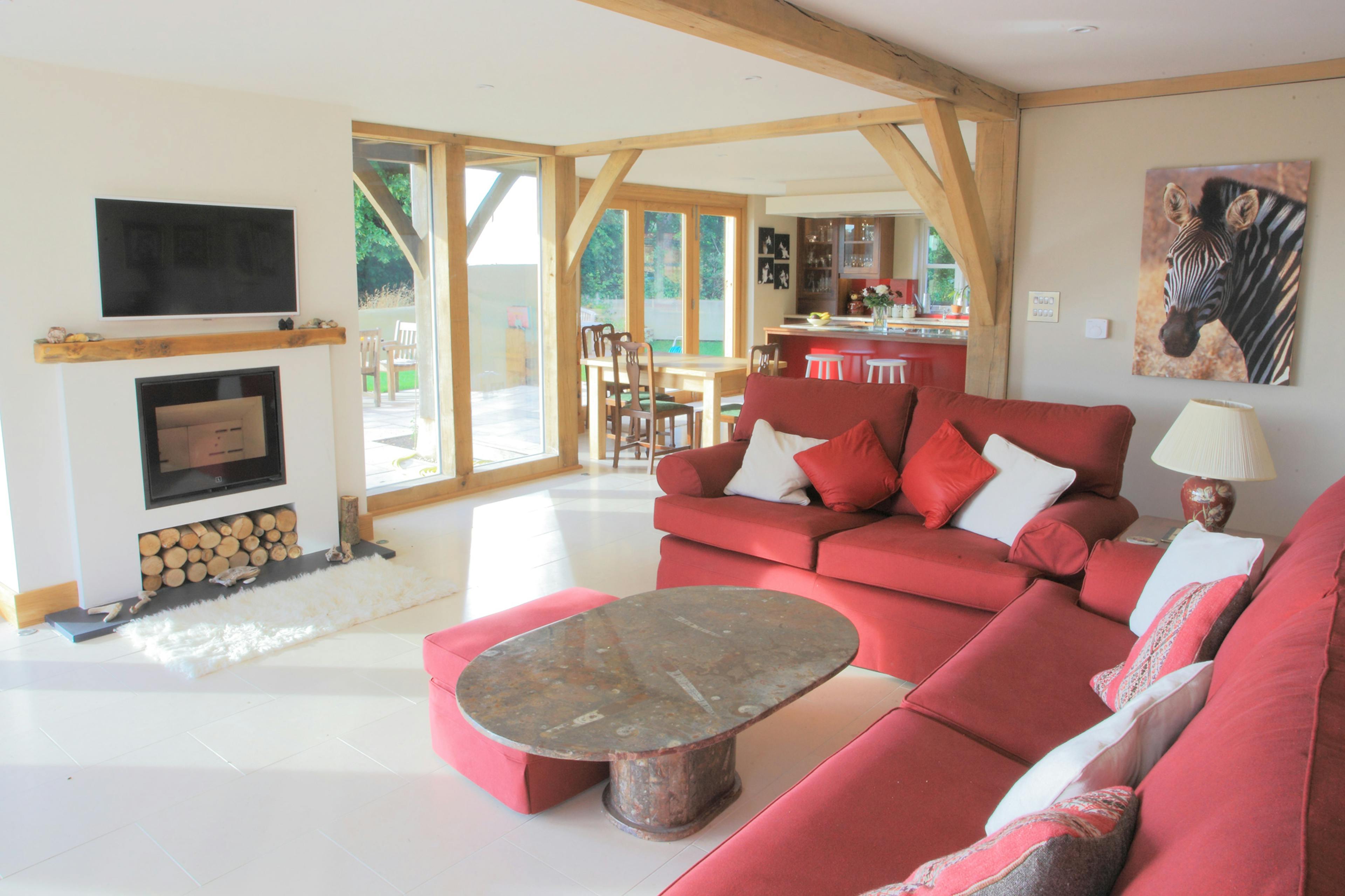 An oak framed sitting room with red sofas and a log burner