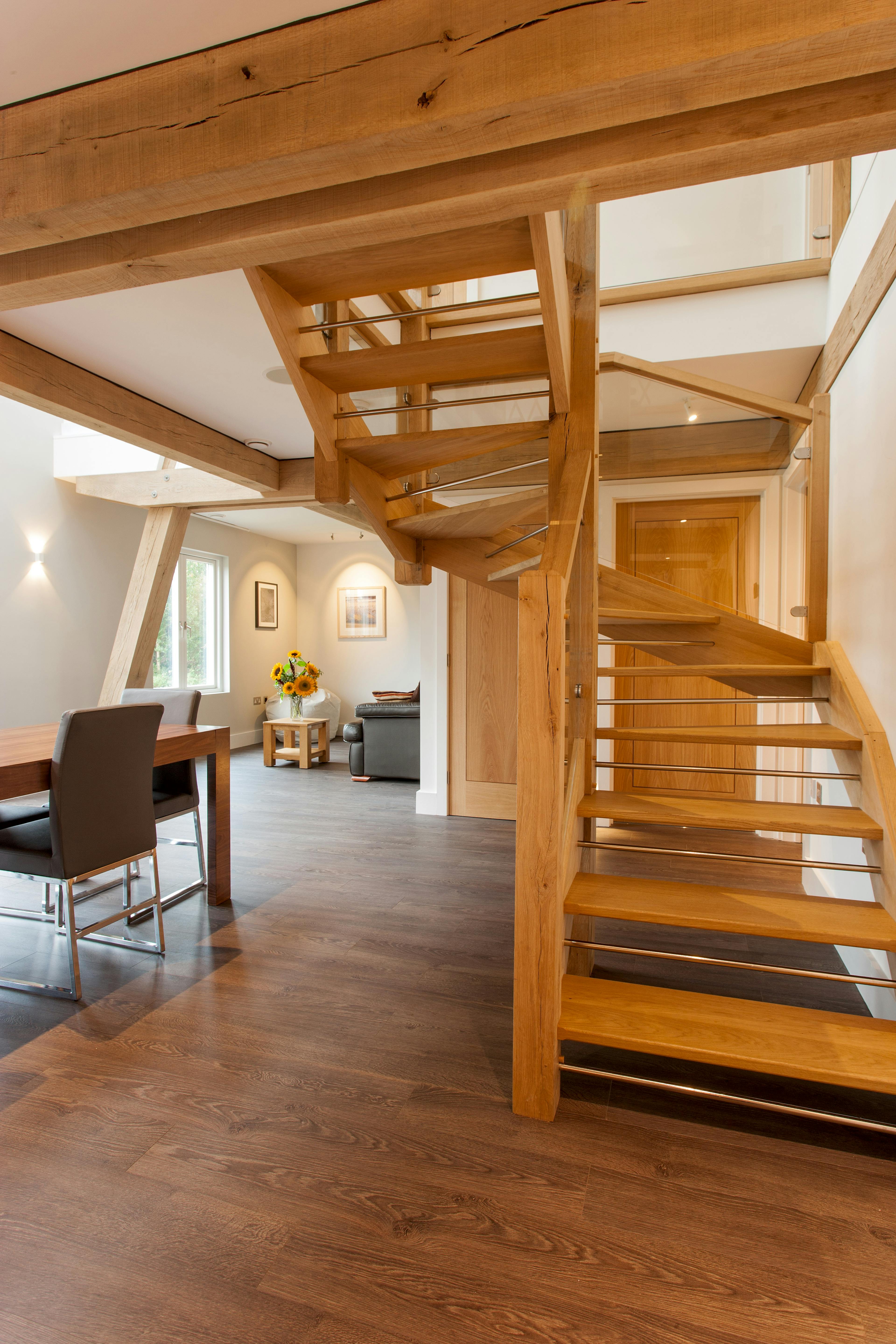 A dining area in a modern oak and steel framed home with a wooden staircase