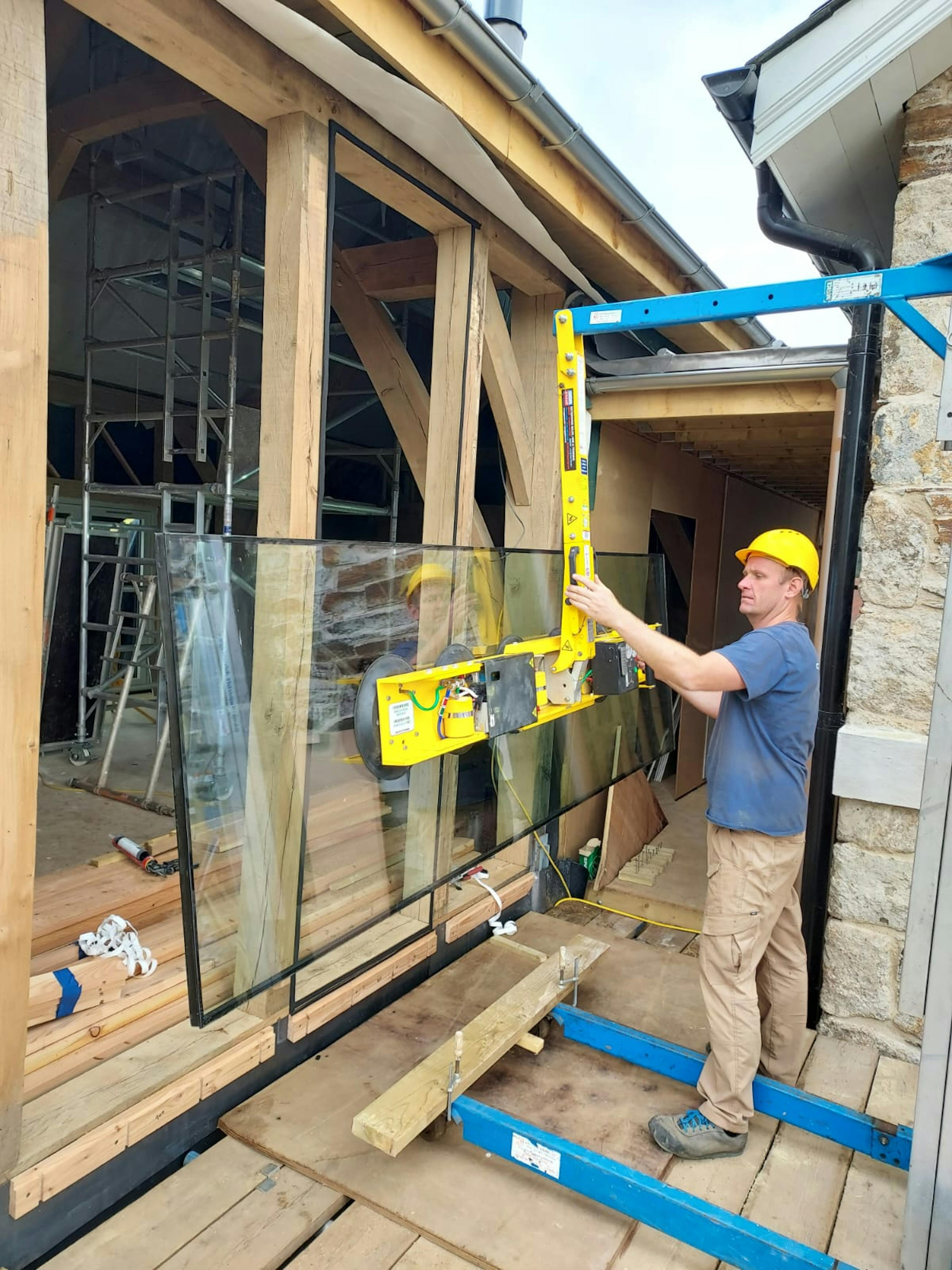 A glazing specialist uses a tool to place a large piece of glazing into place