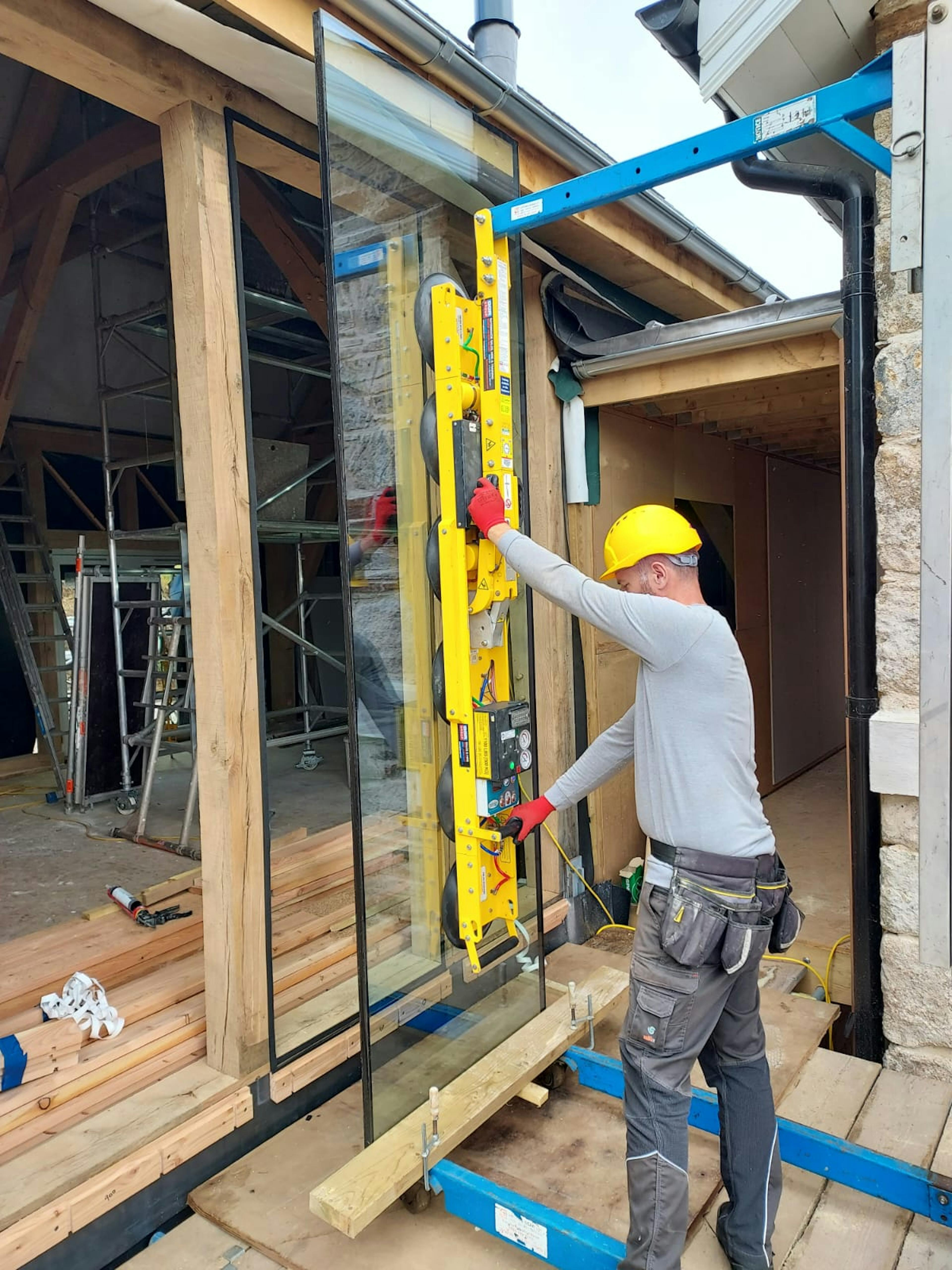 A glazing specialist uses a tool to place a large piece of glazing into place
