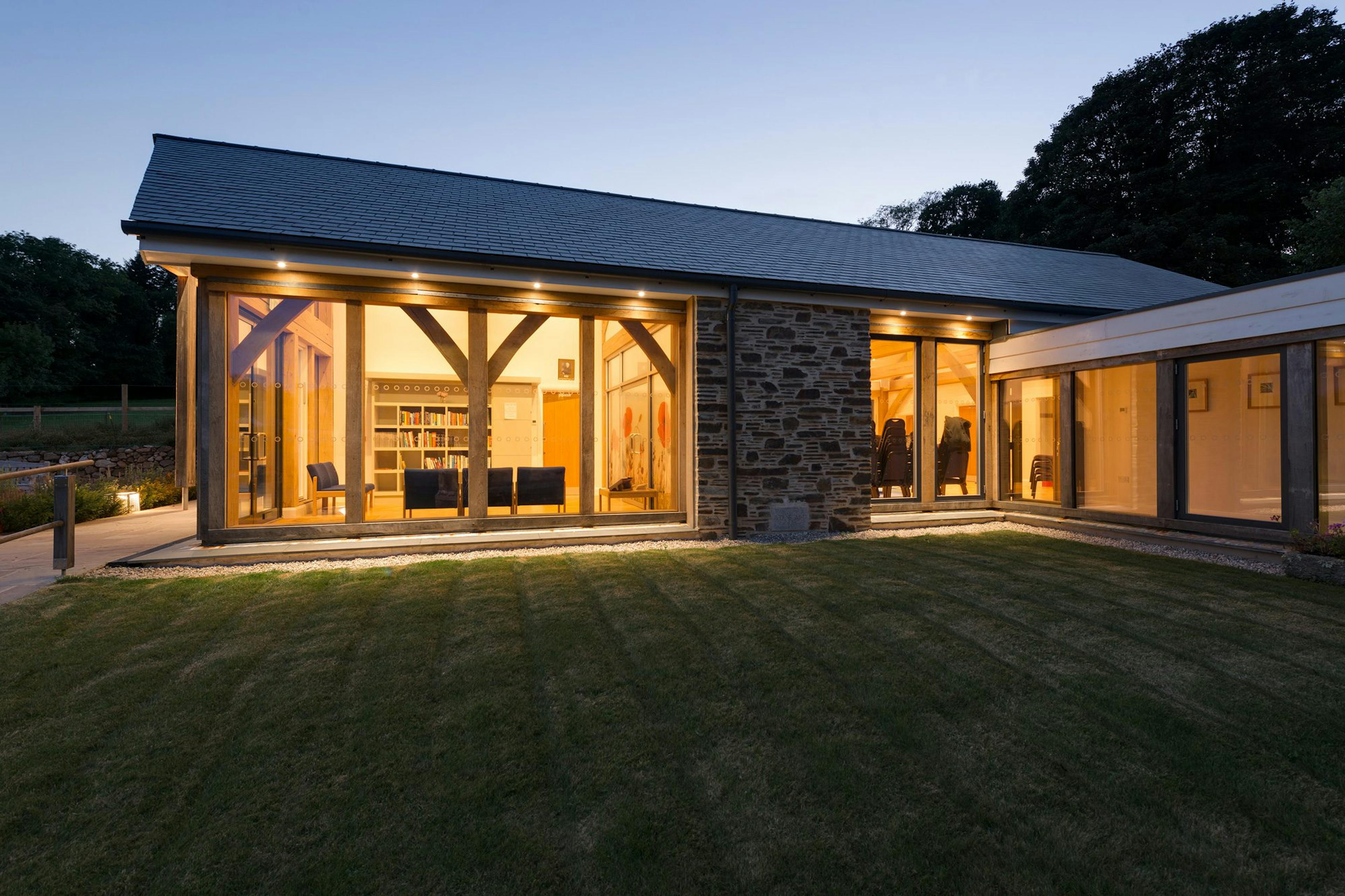 At dusk the light shines from an oak framed hall adjoined to a church