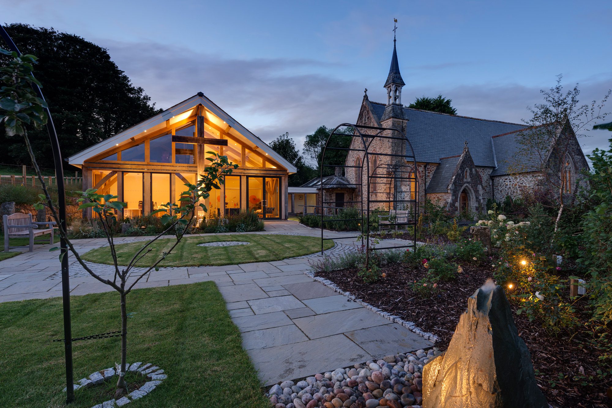 At dusk the light shines from an oak framed hall adjoined to a church