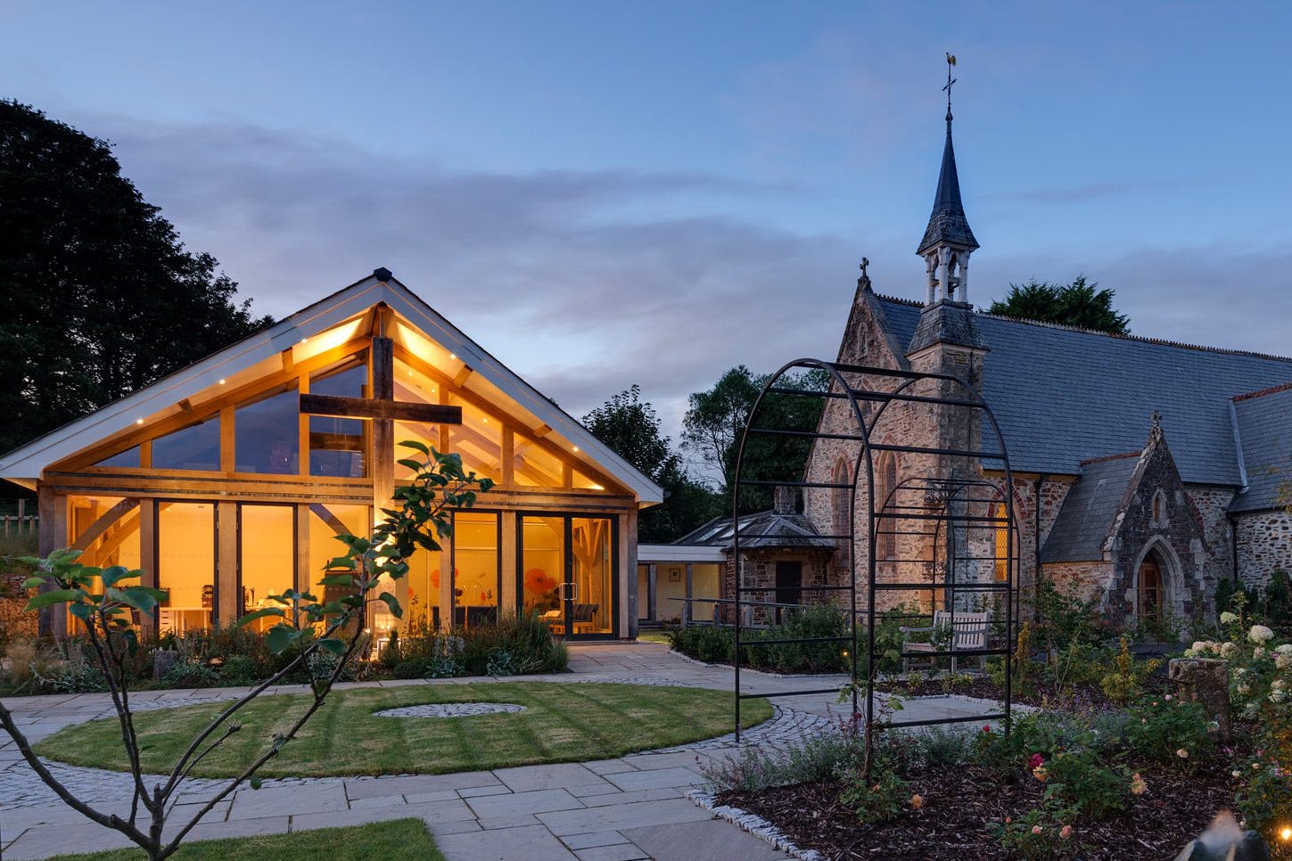 At dusk the light shines from an oak framed hall adjoined to a church