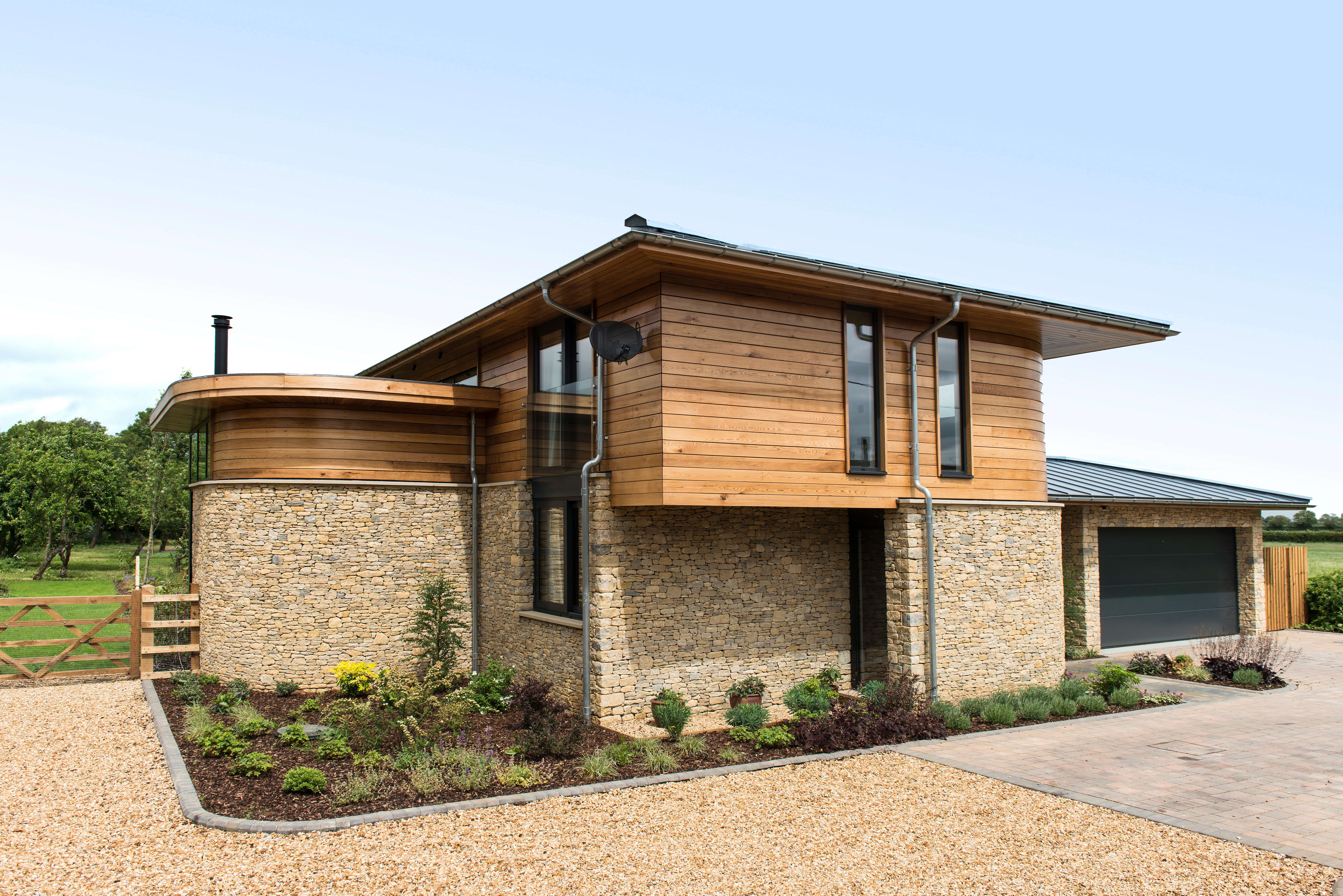 The rear of a modern two storey oak framed home with a garage