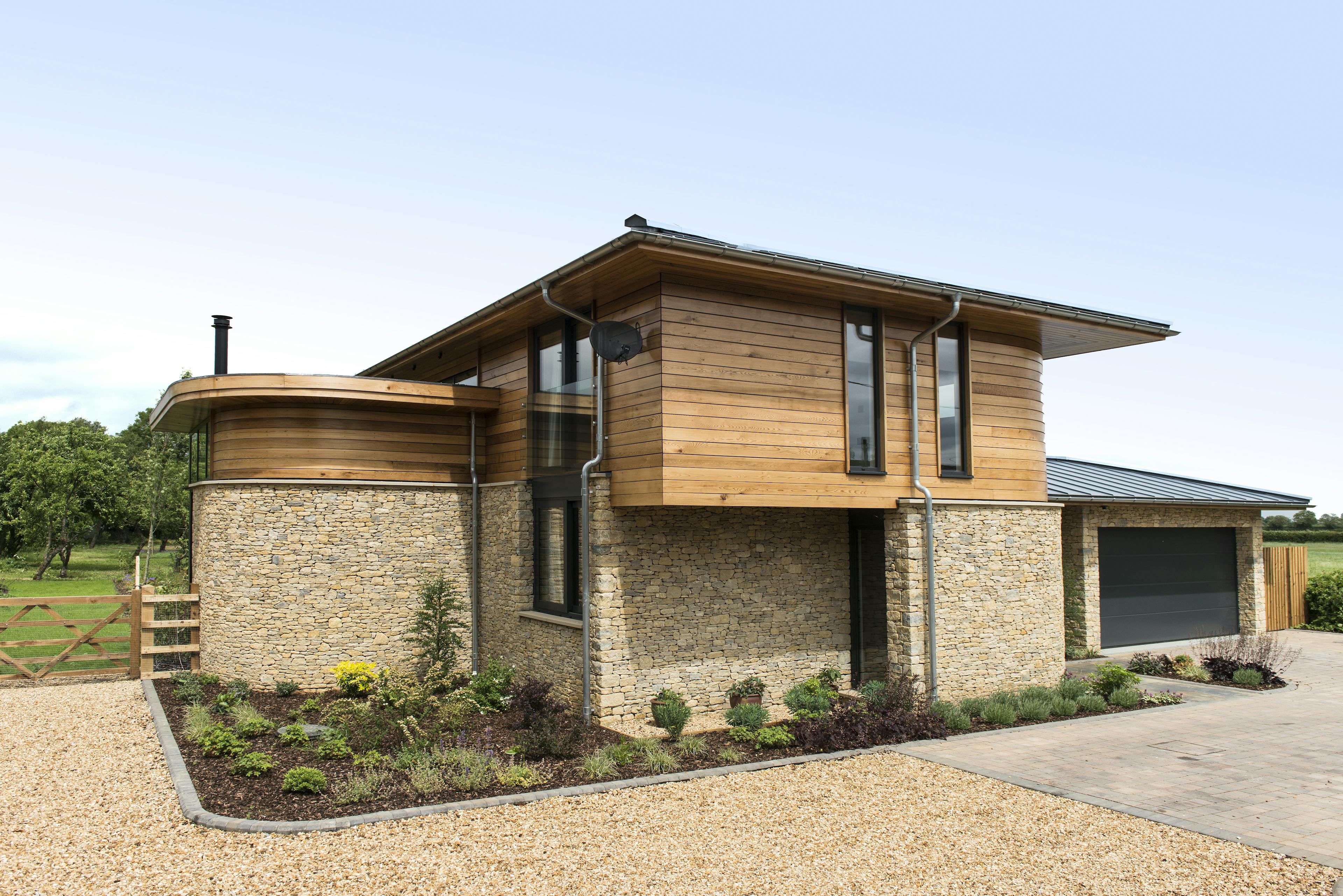 The rear of a modern two storey oak framed home with a garage