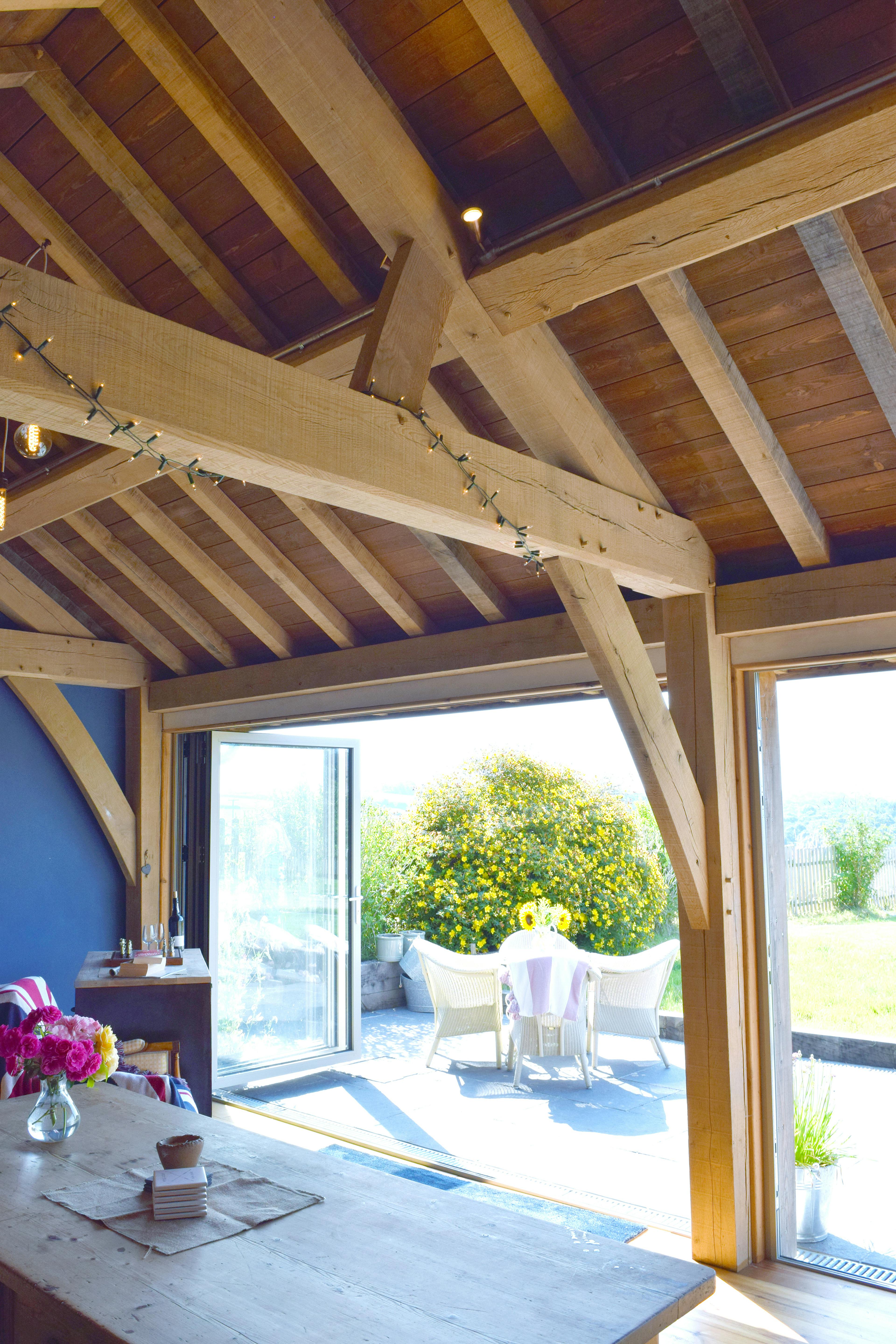 The inside of a 2-bay oak framed extension with bi fold doors opening out to a garden
