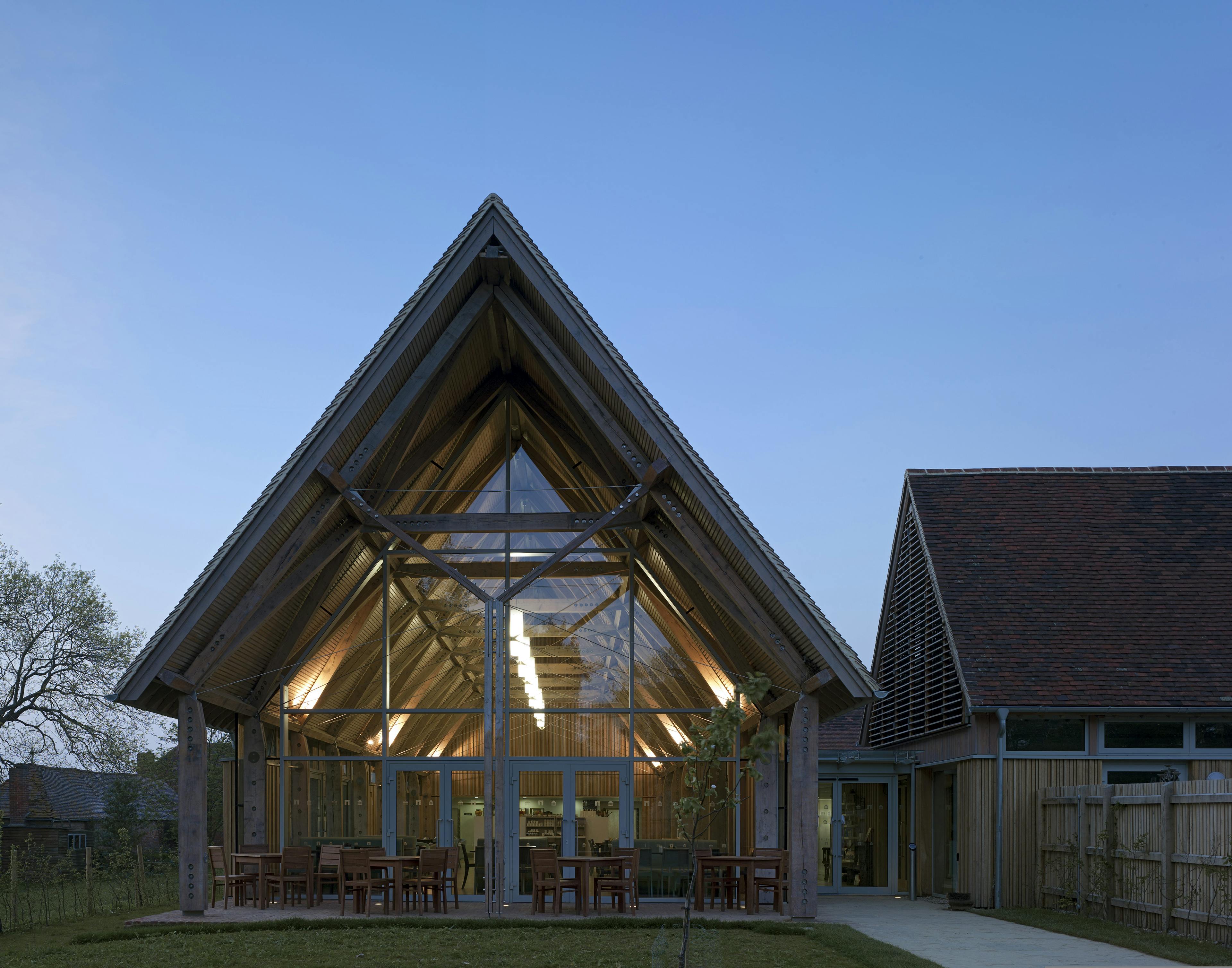 At dusk a visitors centre and cafe made with a diagrid roof constructed from larch