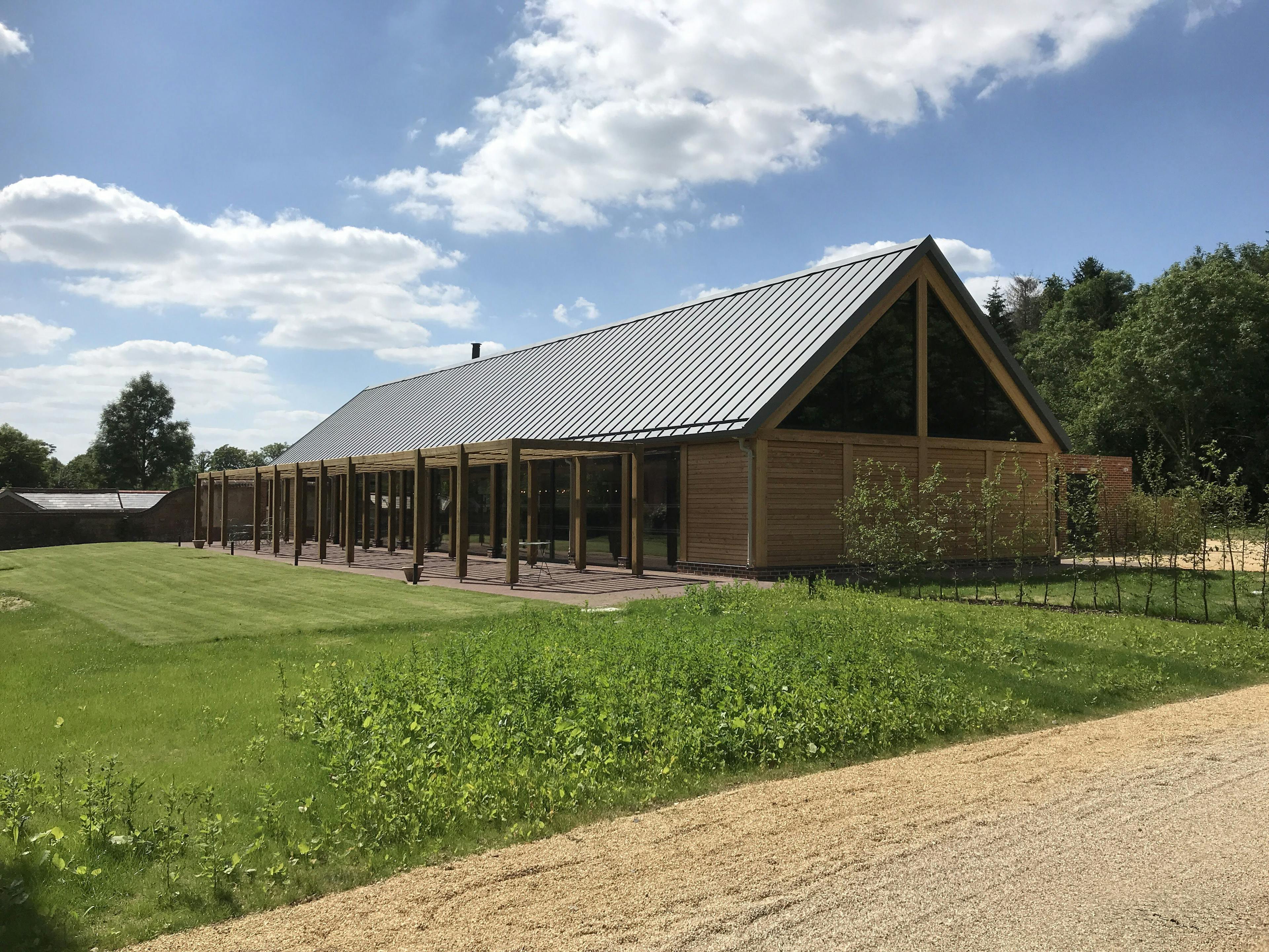 A timber white spruce glulam wedding barn next to a green lawn