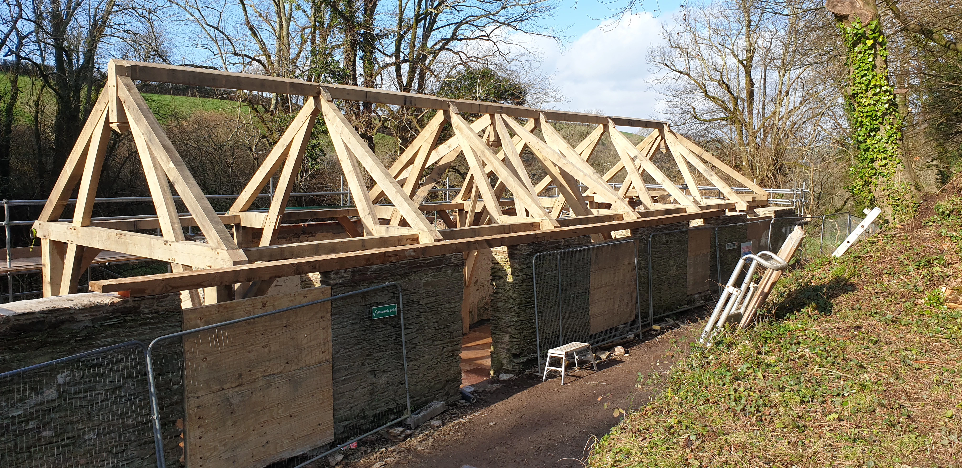 Installation site showcasing an oak frame being assembled within an existing stone barn