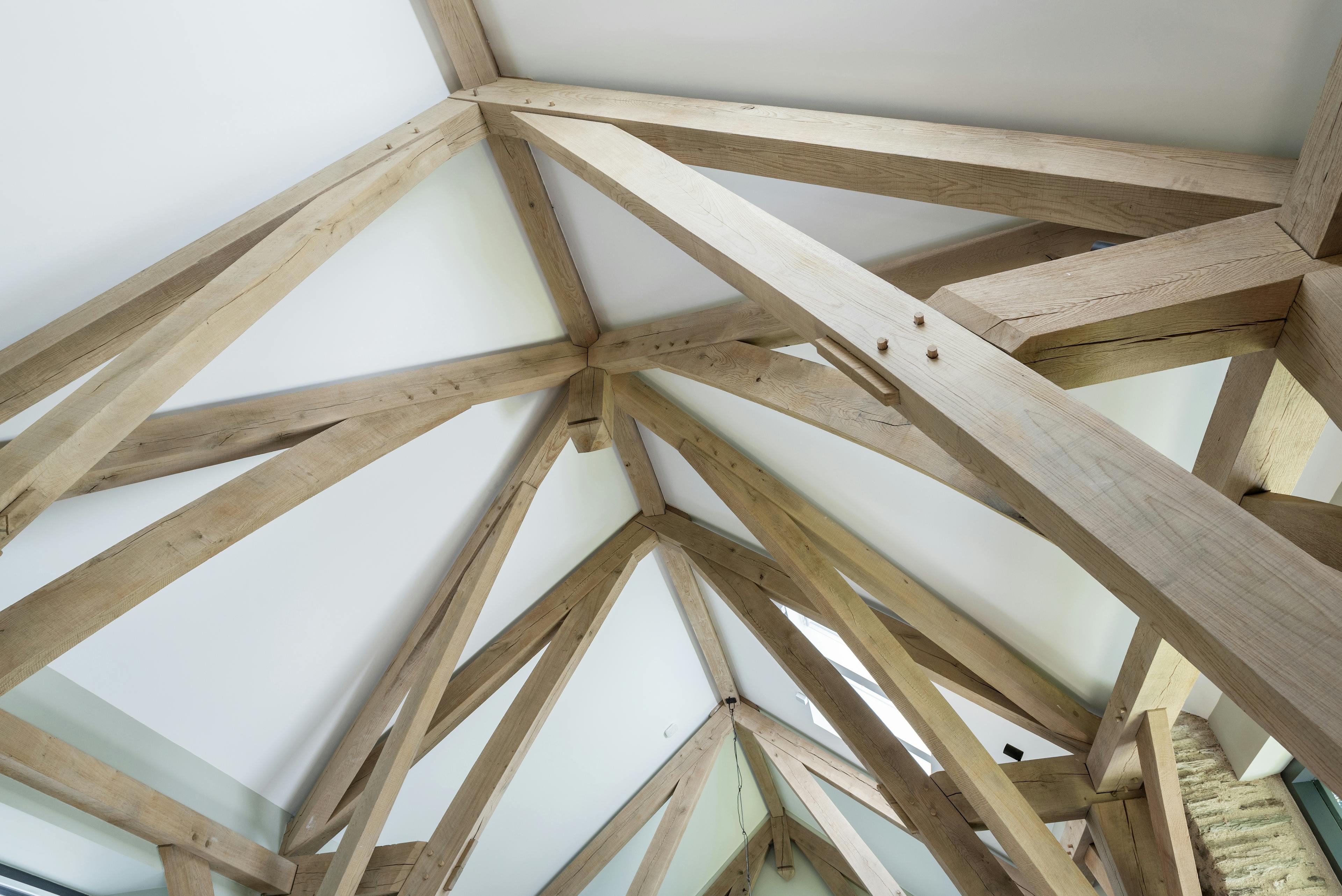 Vaulted ceiling in an open-plan living room, formed by oak sling-brace trusses