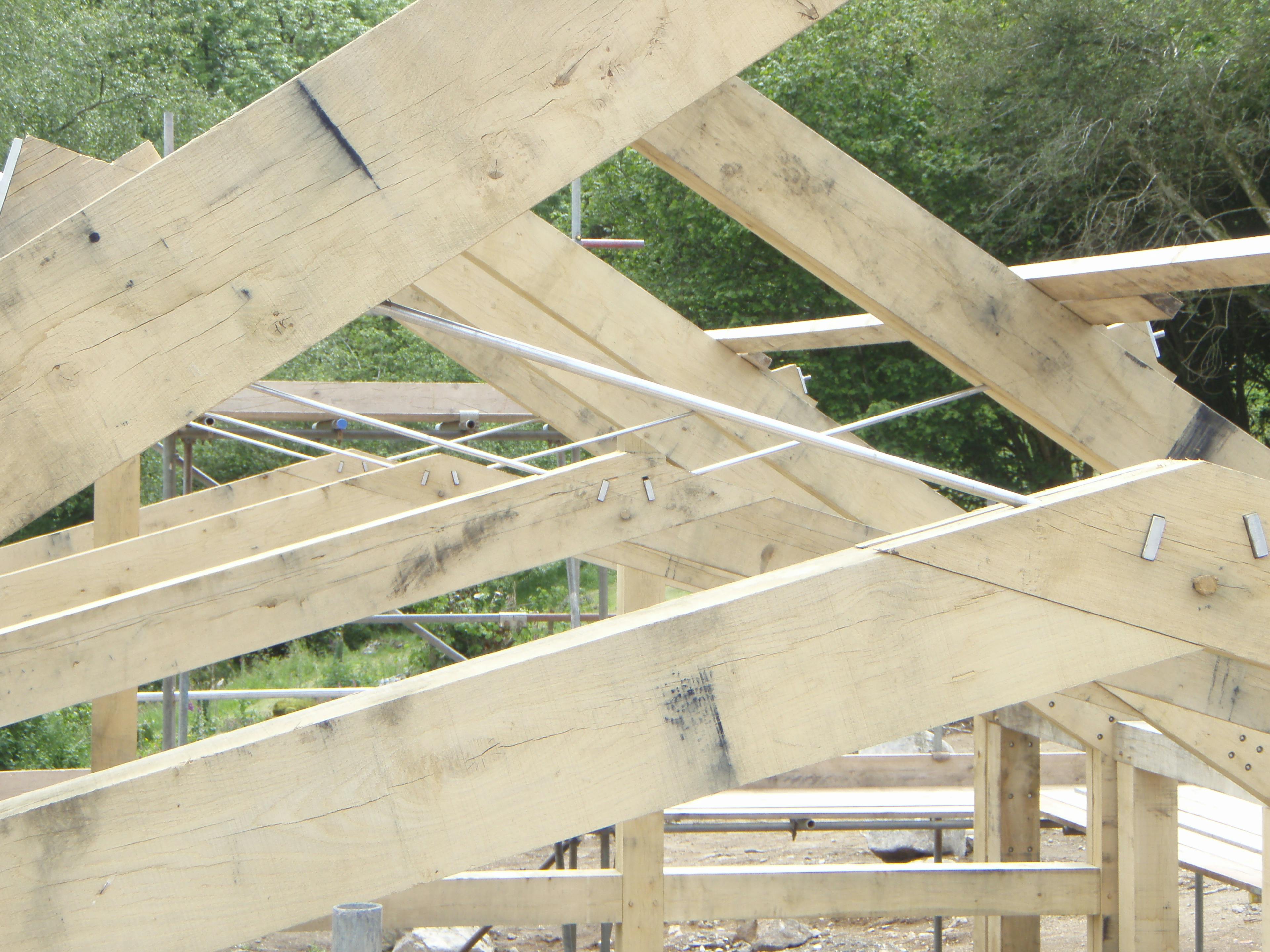 Close-up view of steel connectors and tie rods within oak frame trusses