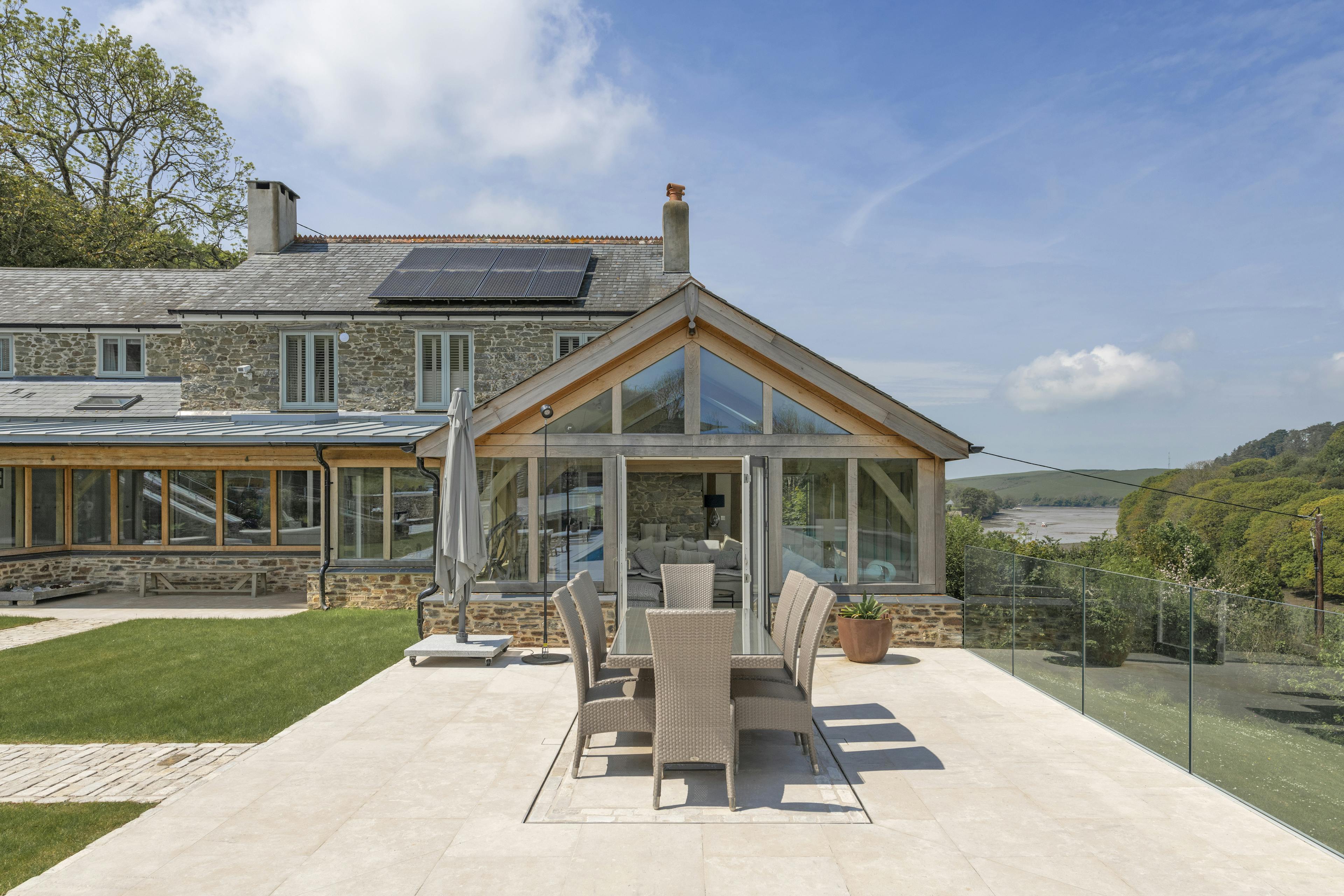 A renovated cottage on an estuary with an oak framed garden room extension opening out onto a patio