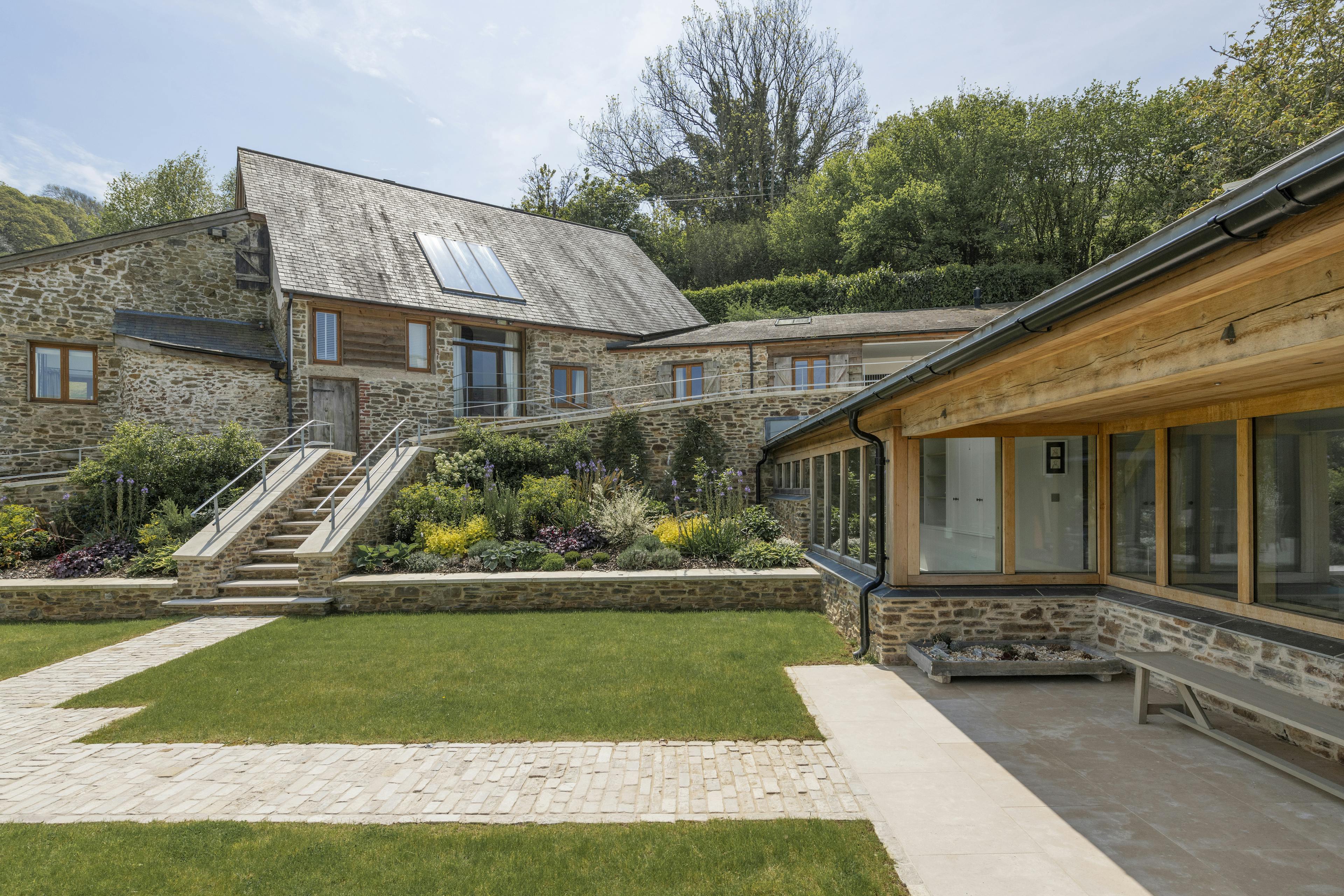 A renovated cottage with a a green lawn, and oak framed garden room, entrance and corridor extension