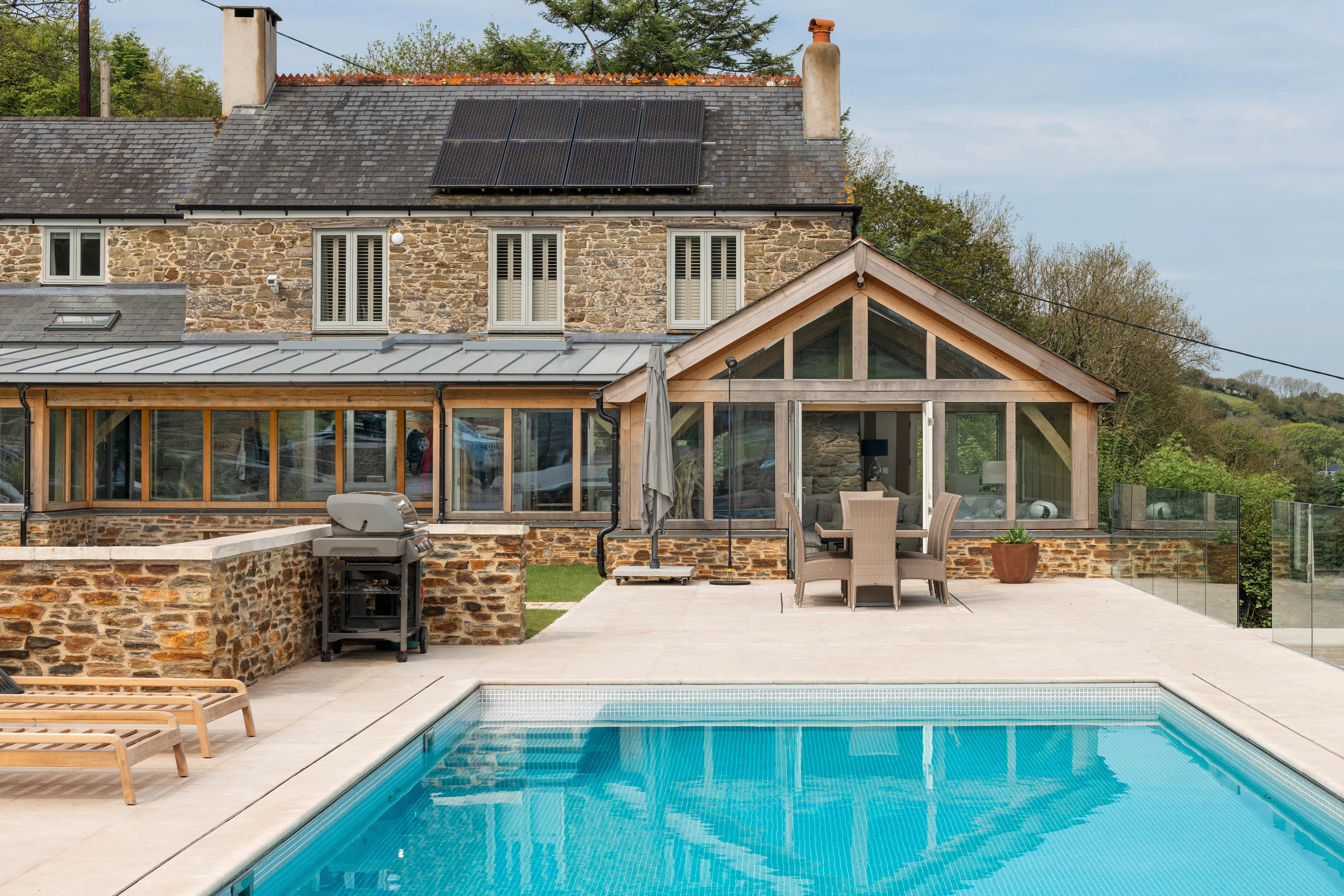 A renovated cottage on an estuary with a a swimming pool, green lawn and oak framed garden room, entrance and corridor extension