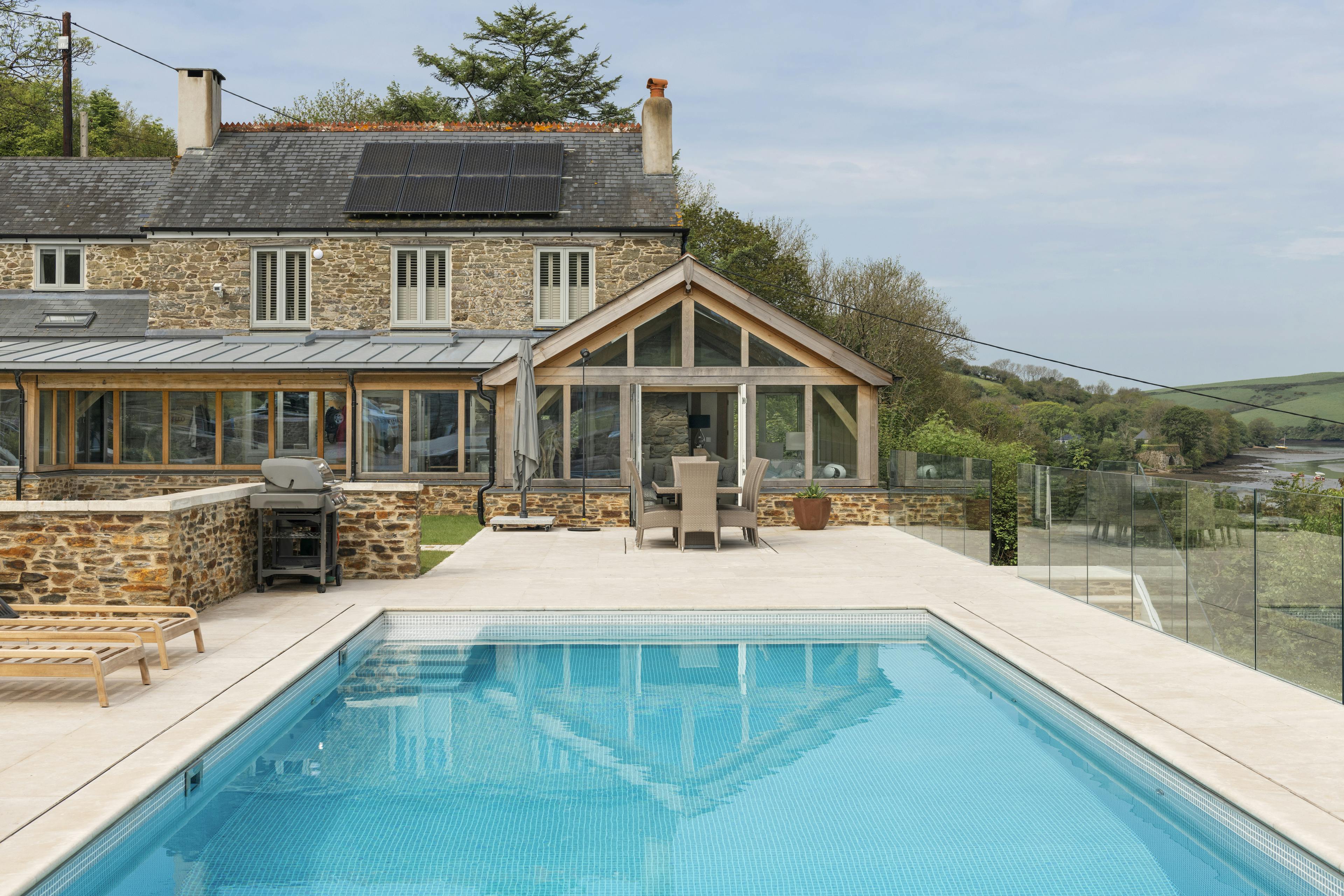 A renovated cottage on an estuary with a a swimming pool, green lawn and oak framed garden room, entrance and corridor extension