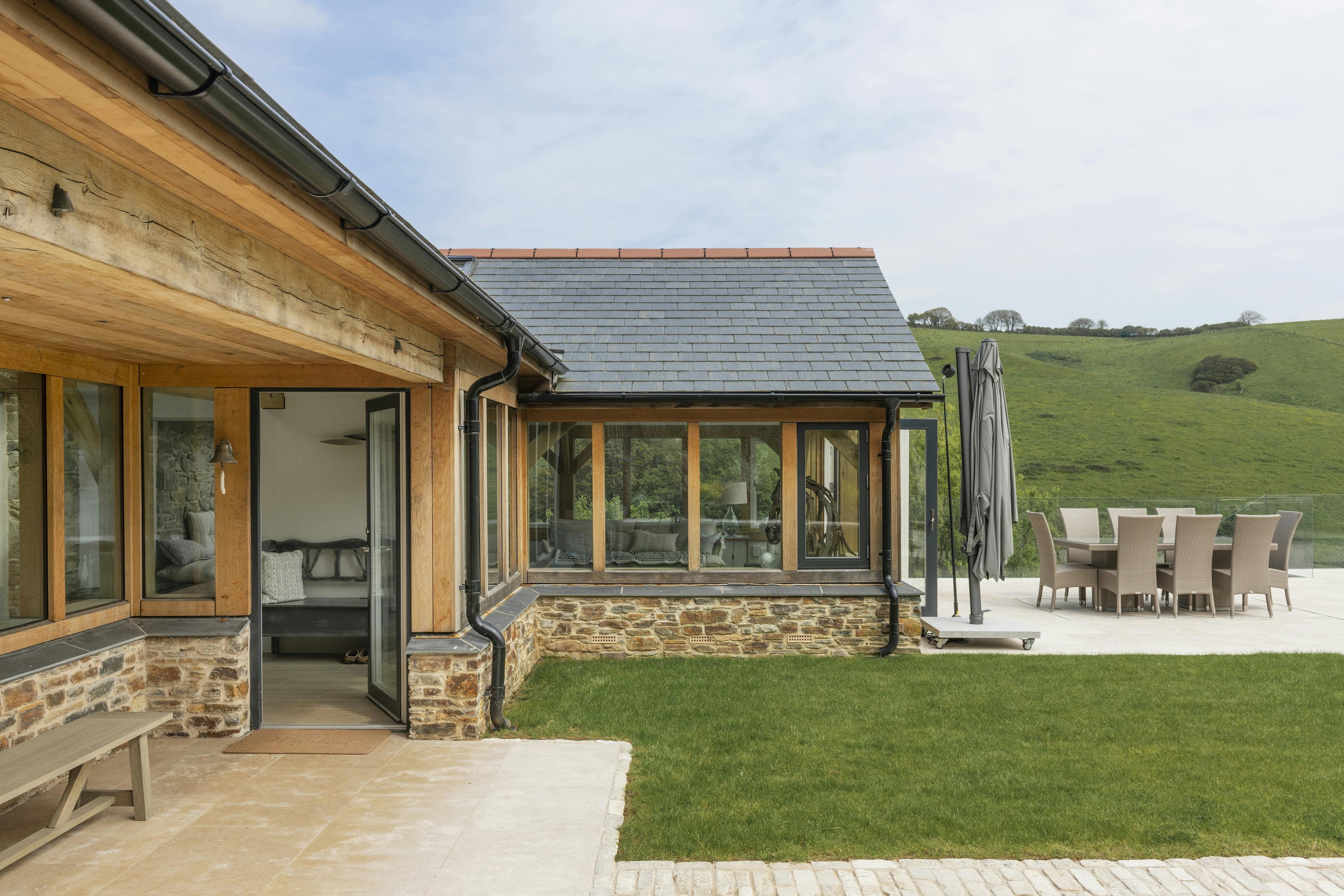 A renovated cottage on an estuary with a green lawn and oak framed garden room, entrance and corridor extension
