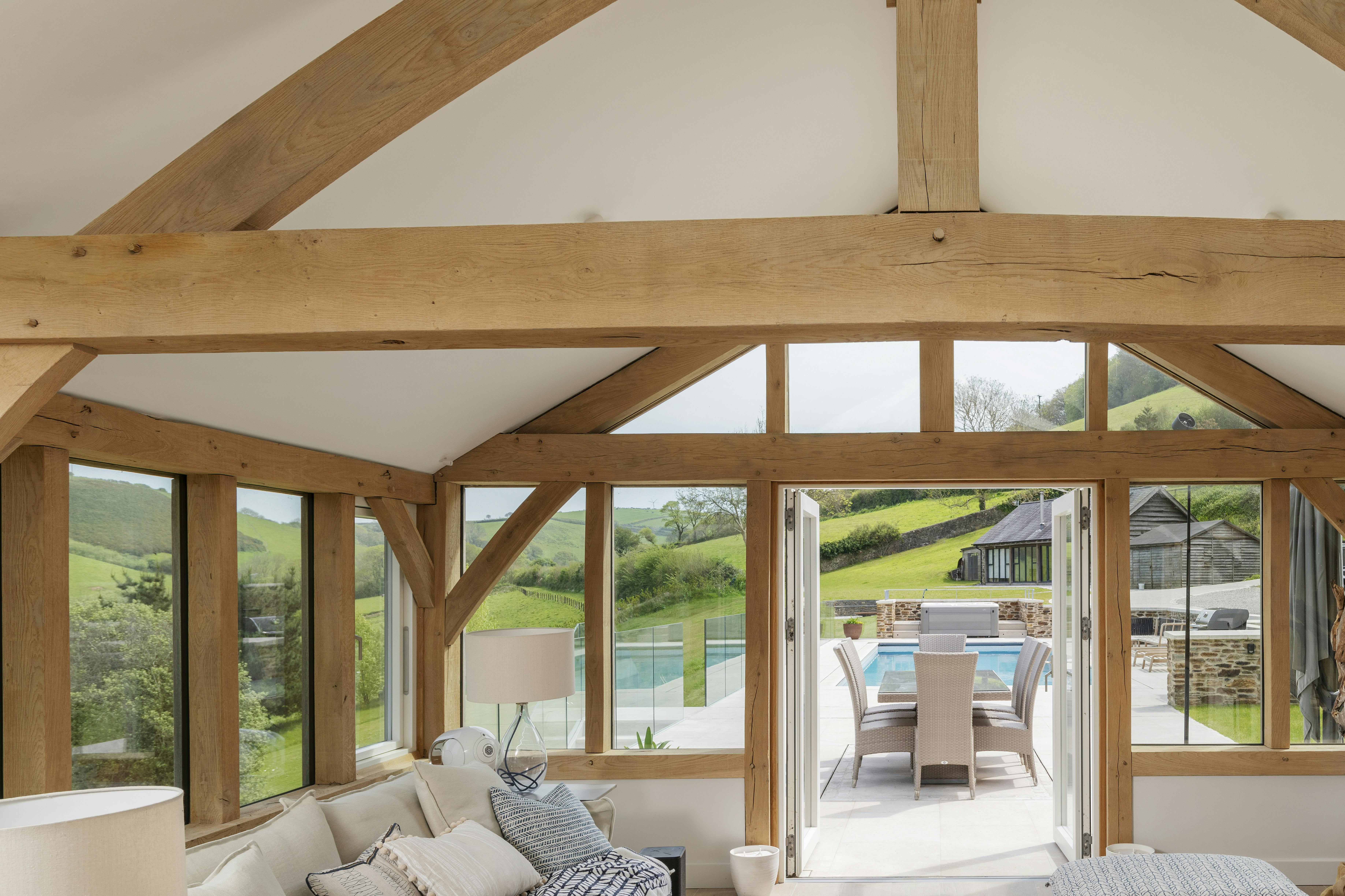 An oak framed garden room extension with French doors to a patio area and swimming pool