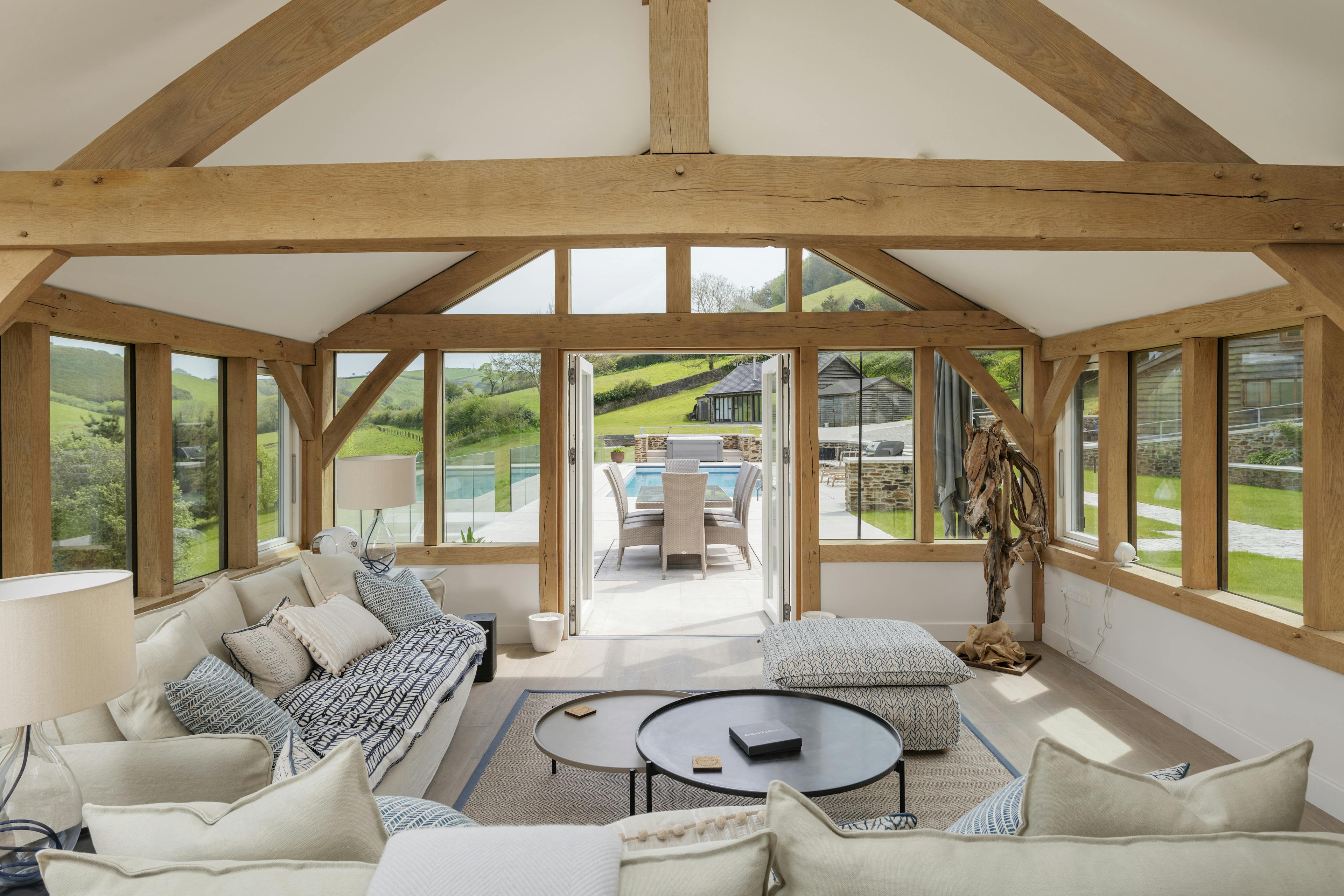 An oak framed garden room extension with French doors to a patio area and swimming pool