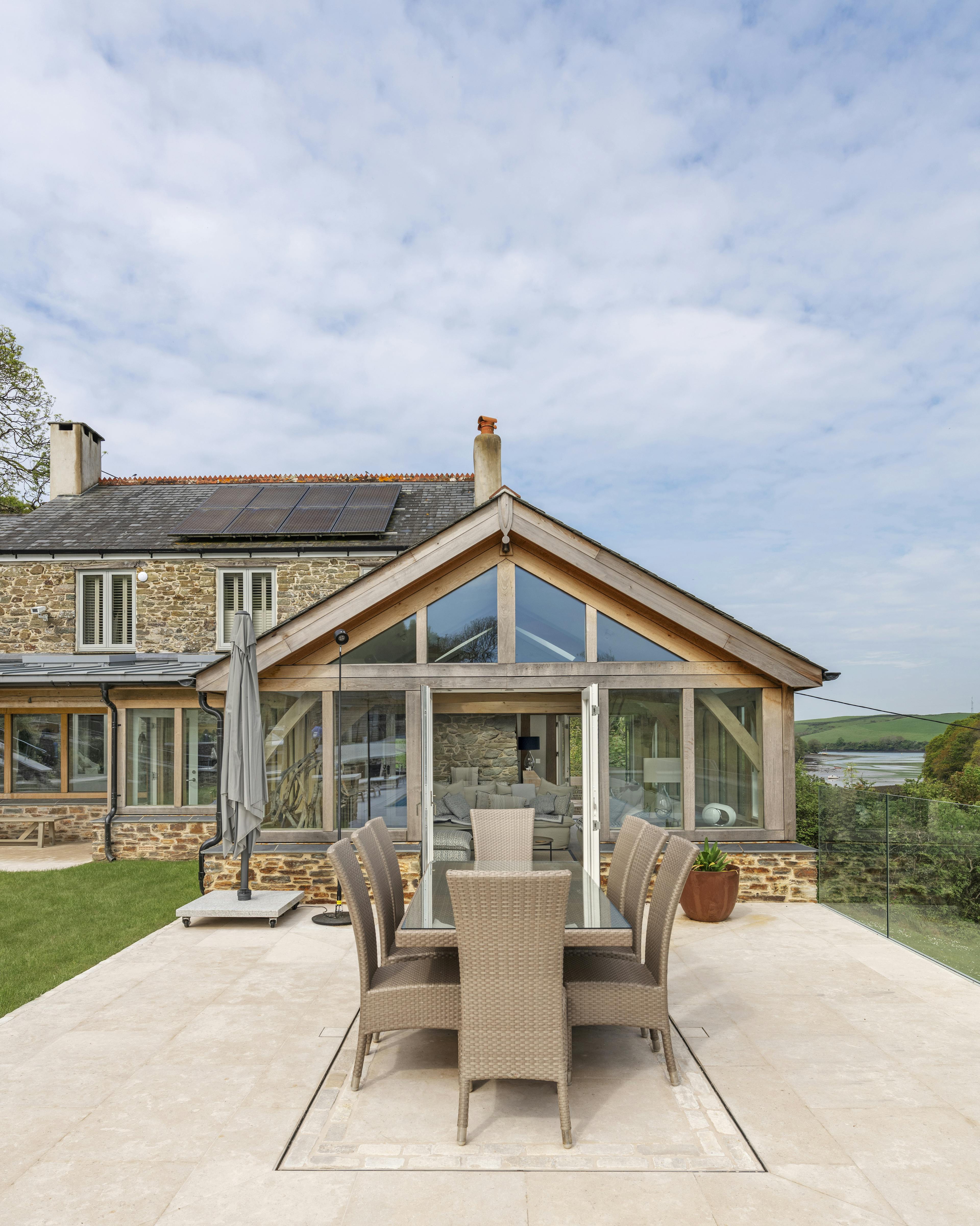A renovated cottage on an estuary with an oak framed garden room extension opening out onto a patio