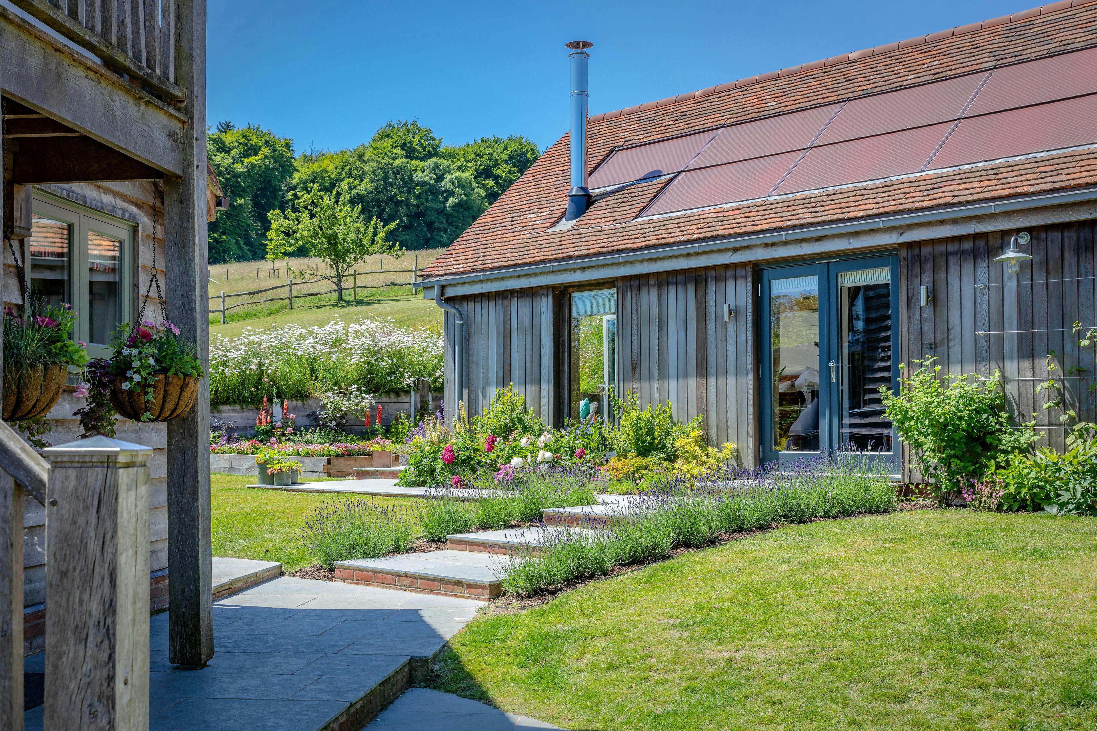 An oak framed garden annexe with a glazed gable end and surrounded by a landscaped garden