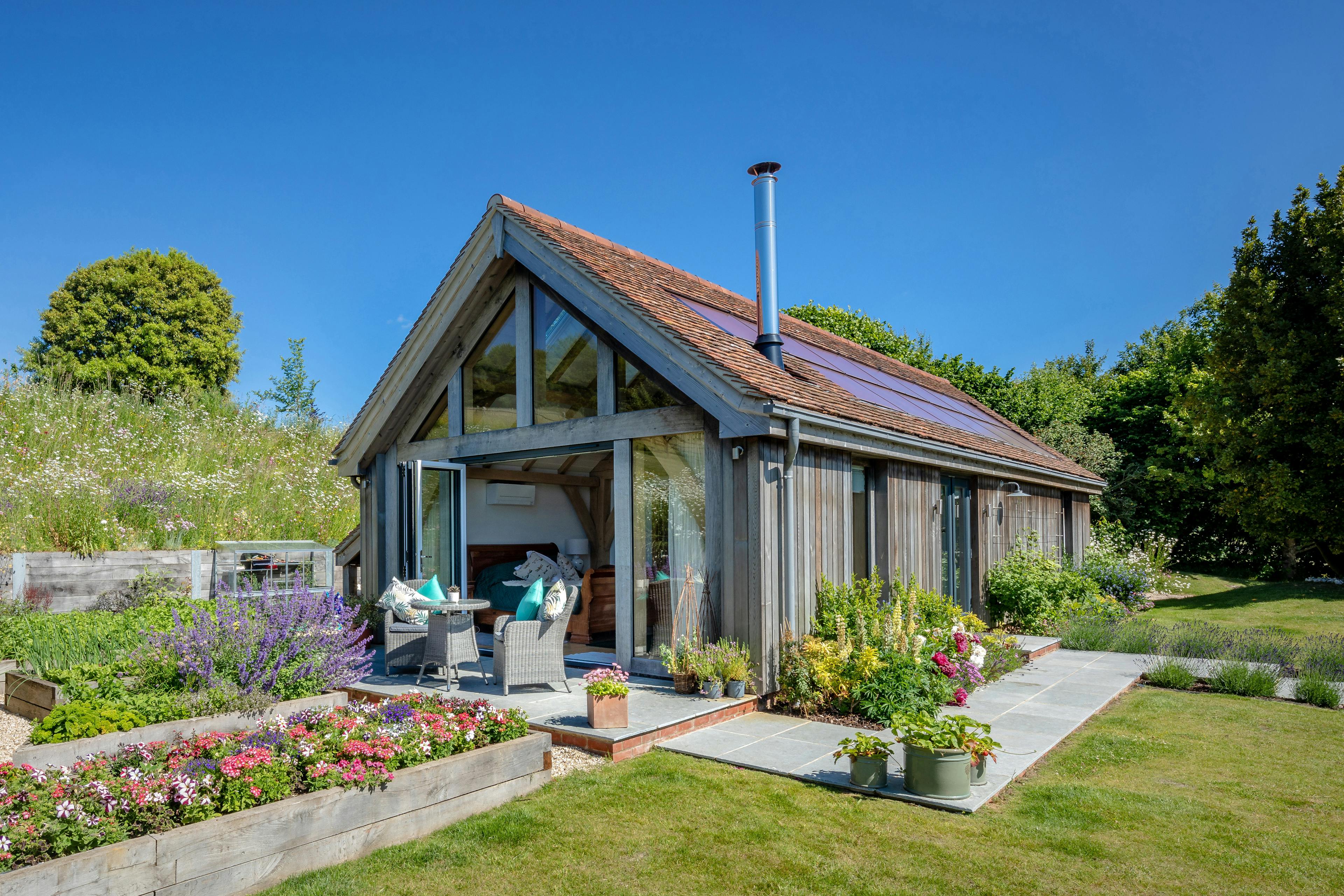 An oak framed garden annex with a glazed gable end and surrounded by a landscaped garden