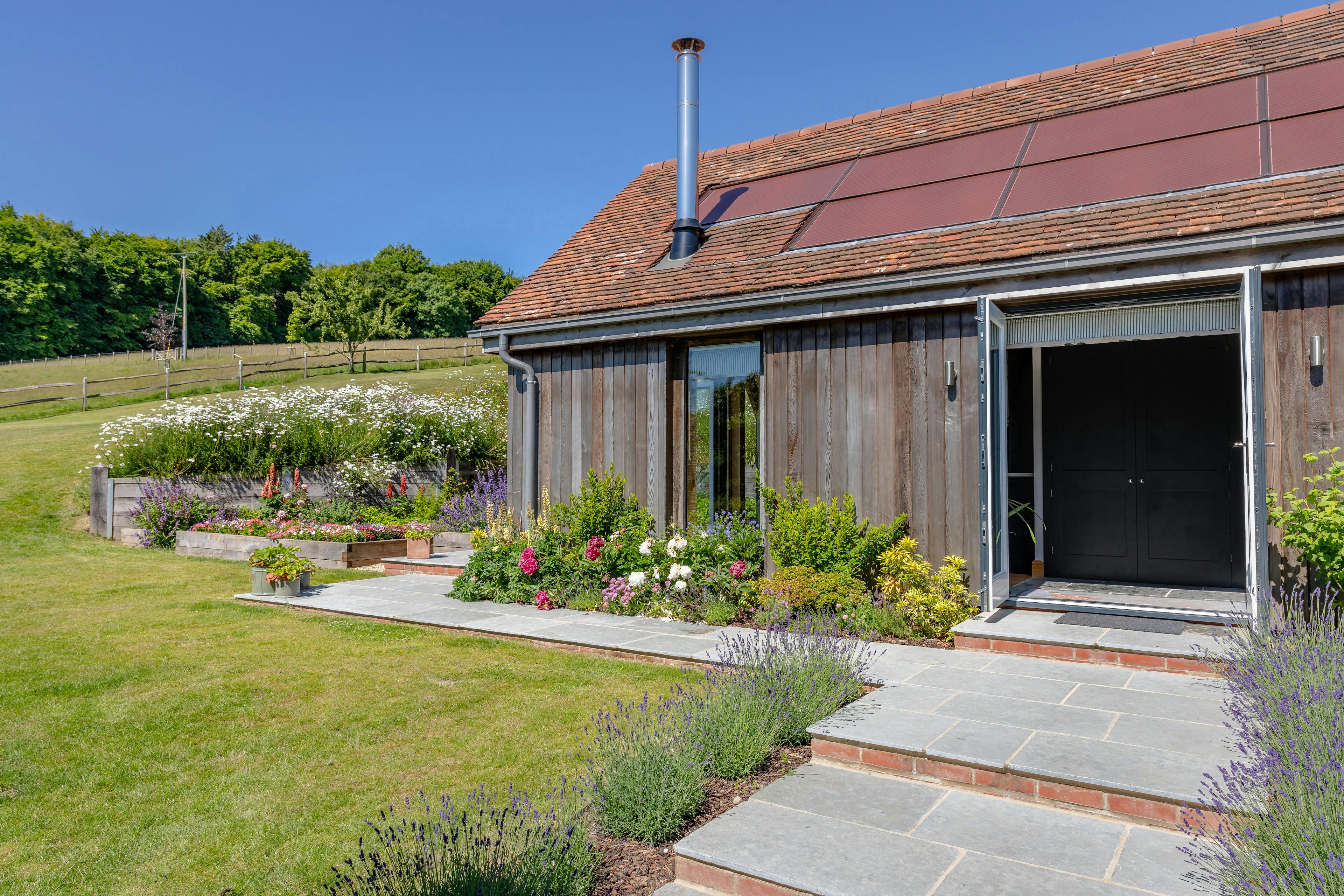 An oak framed garden annex with a glazed gable end and surrounded by a landscaped garden