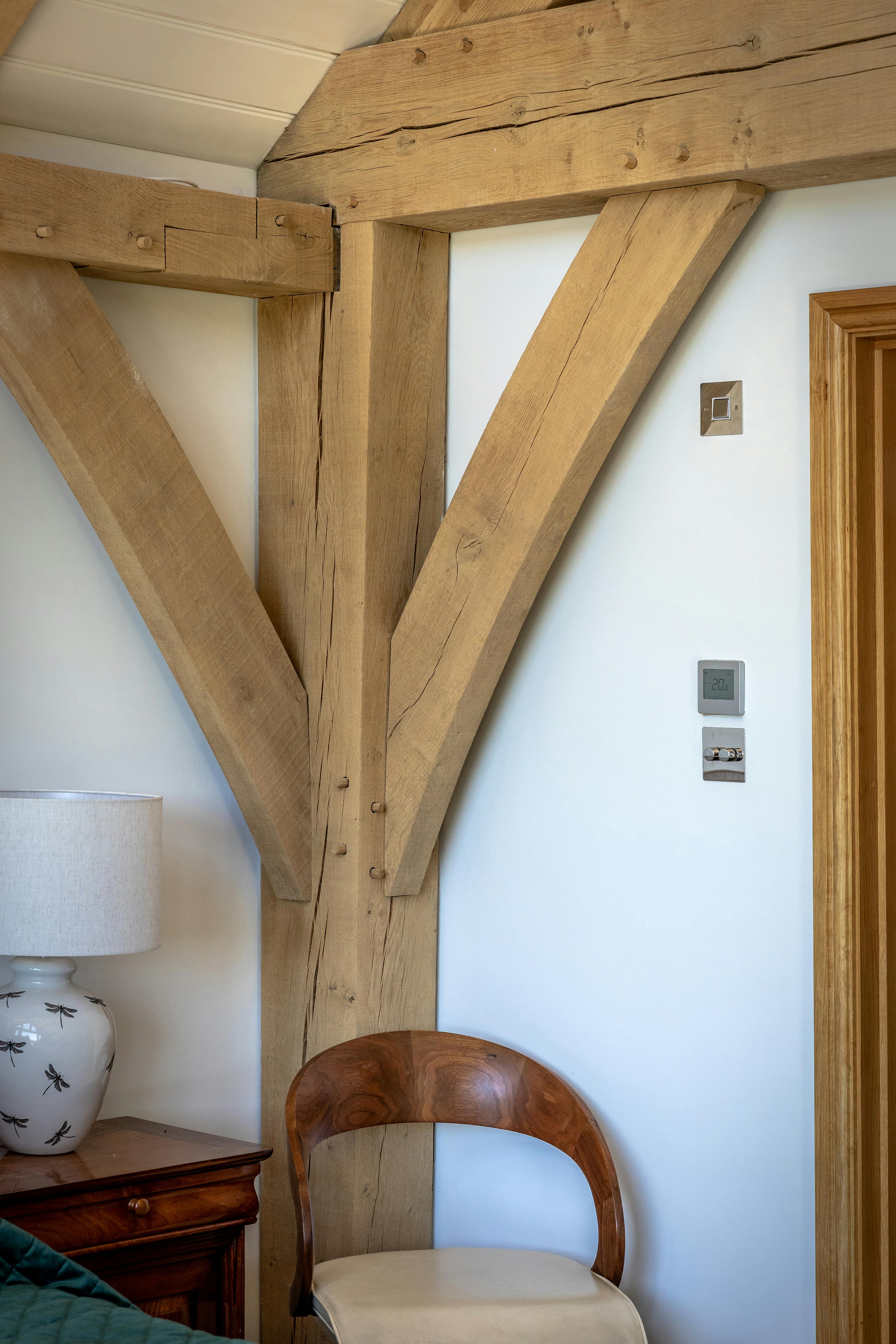 A corner of an oak framed garden annex with a chair and bedside table
